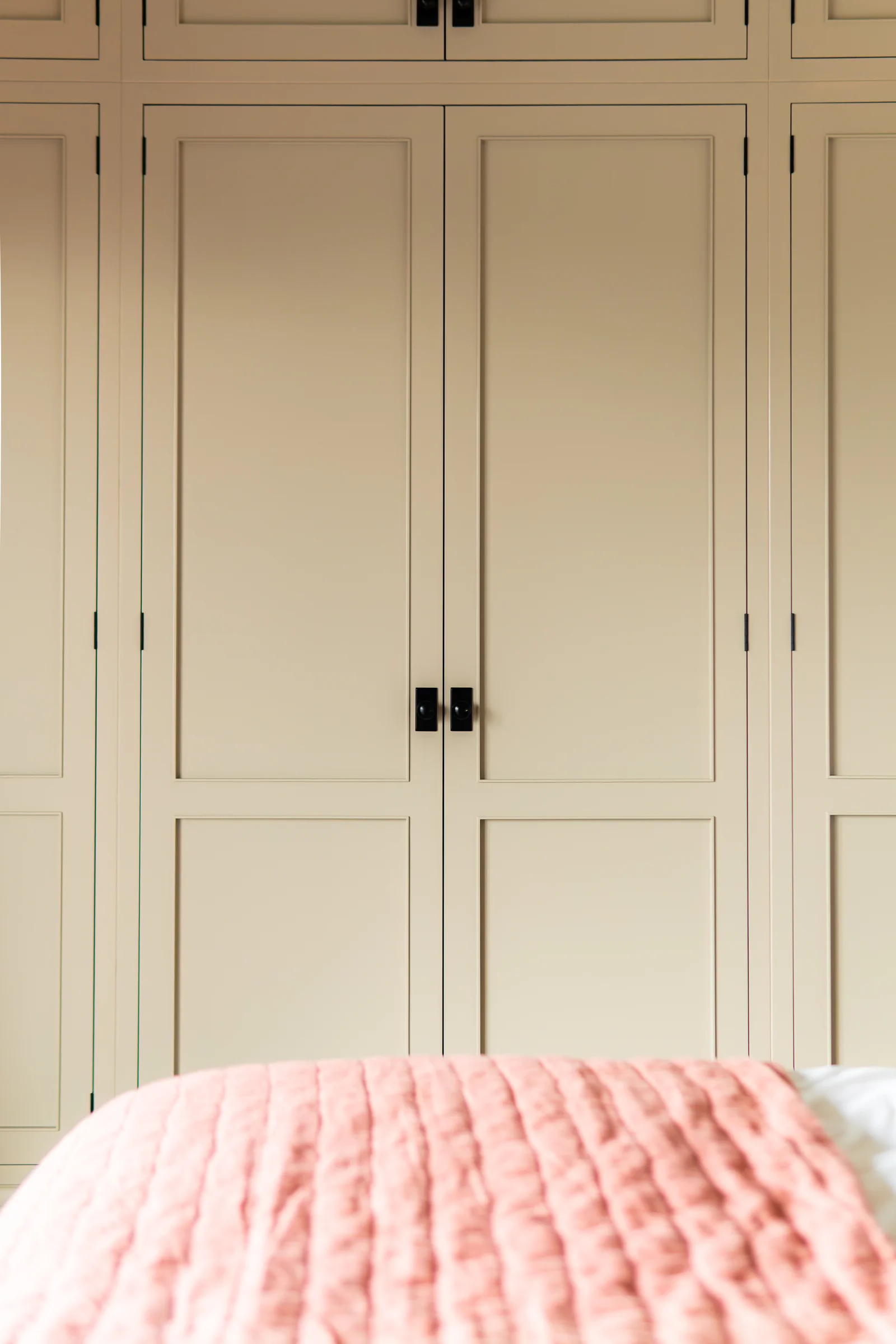 Beige wardrobe doors portrait closeup black knobs pink throw