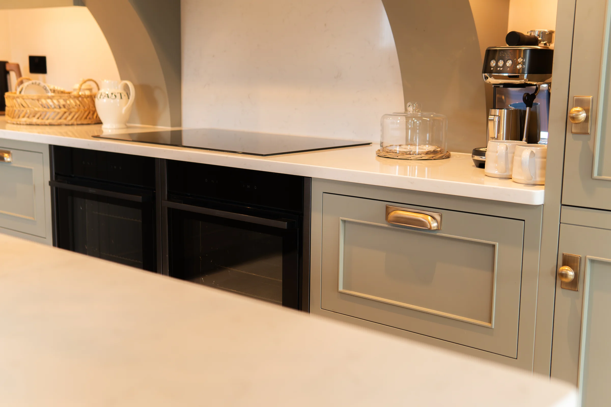 Cooking area induction hob arched quartz extractor recess black ovens grey shaker brass