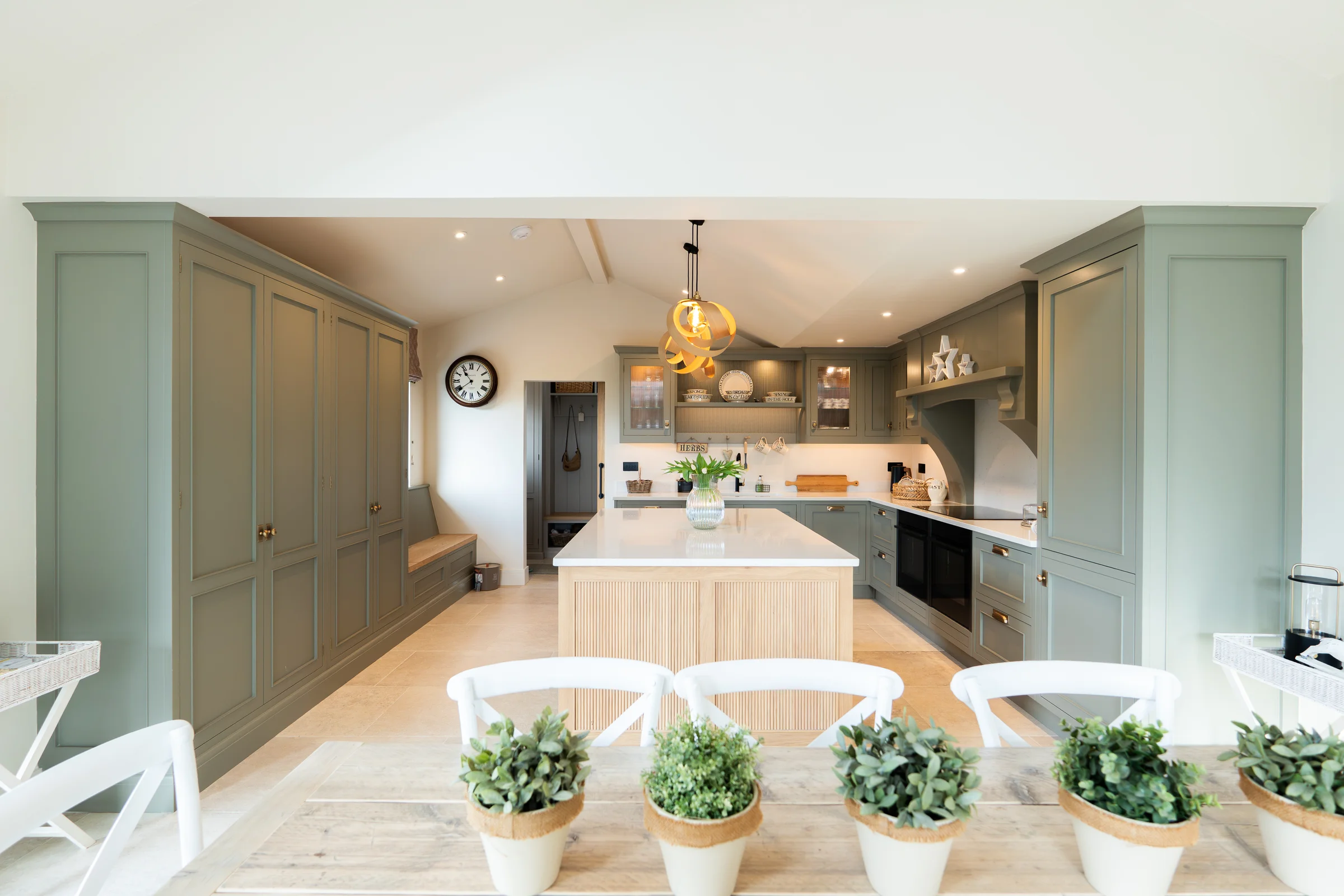 Dining table view into kitchen alt grey units oak island pendant chairs plants