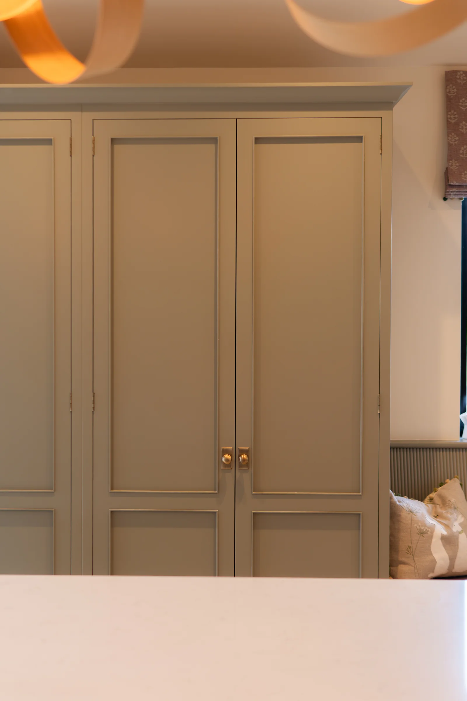Grey pantry cupboard closed brass round knobs wooden ribbon pendant roman blind
