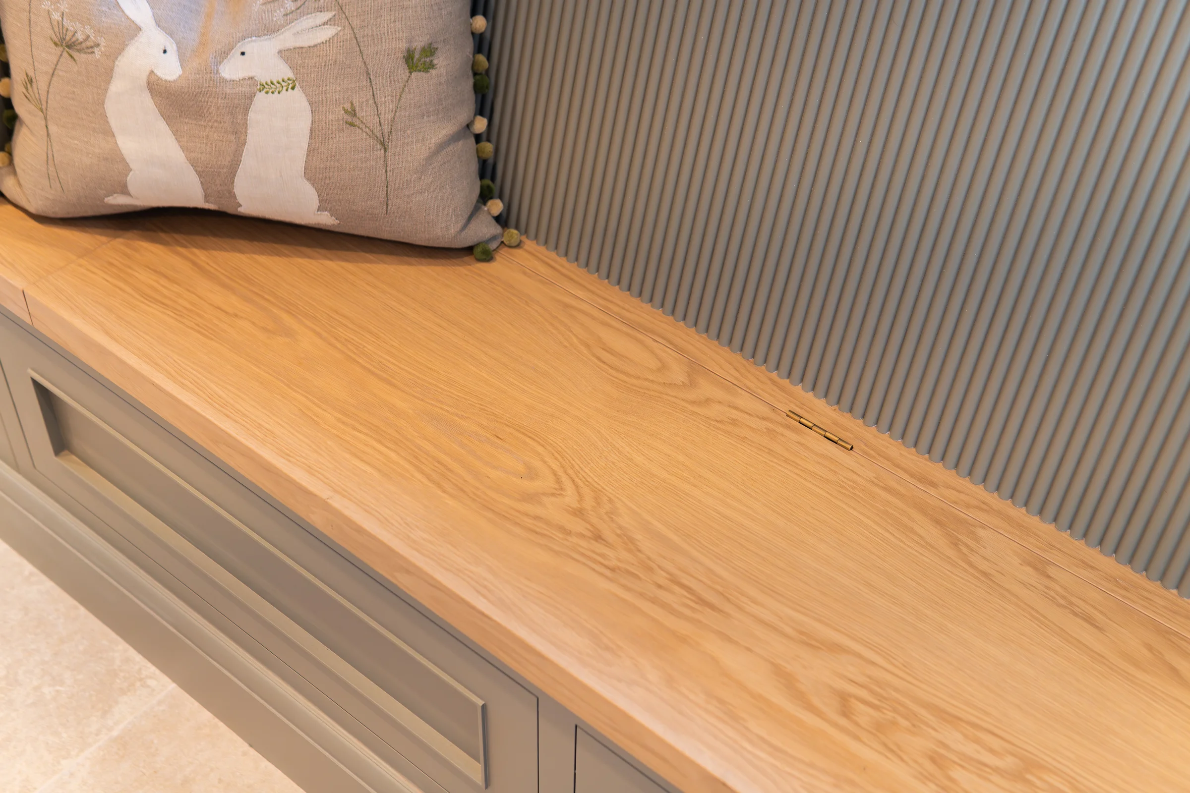 Oak bench seat closeup brass flush hinge reeded slat grey panelling rabbit cushion
