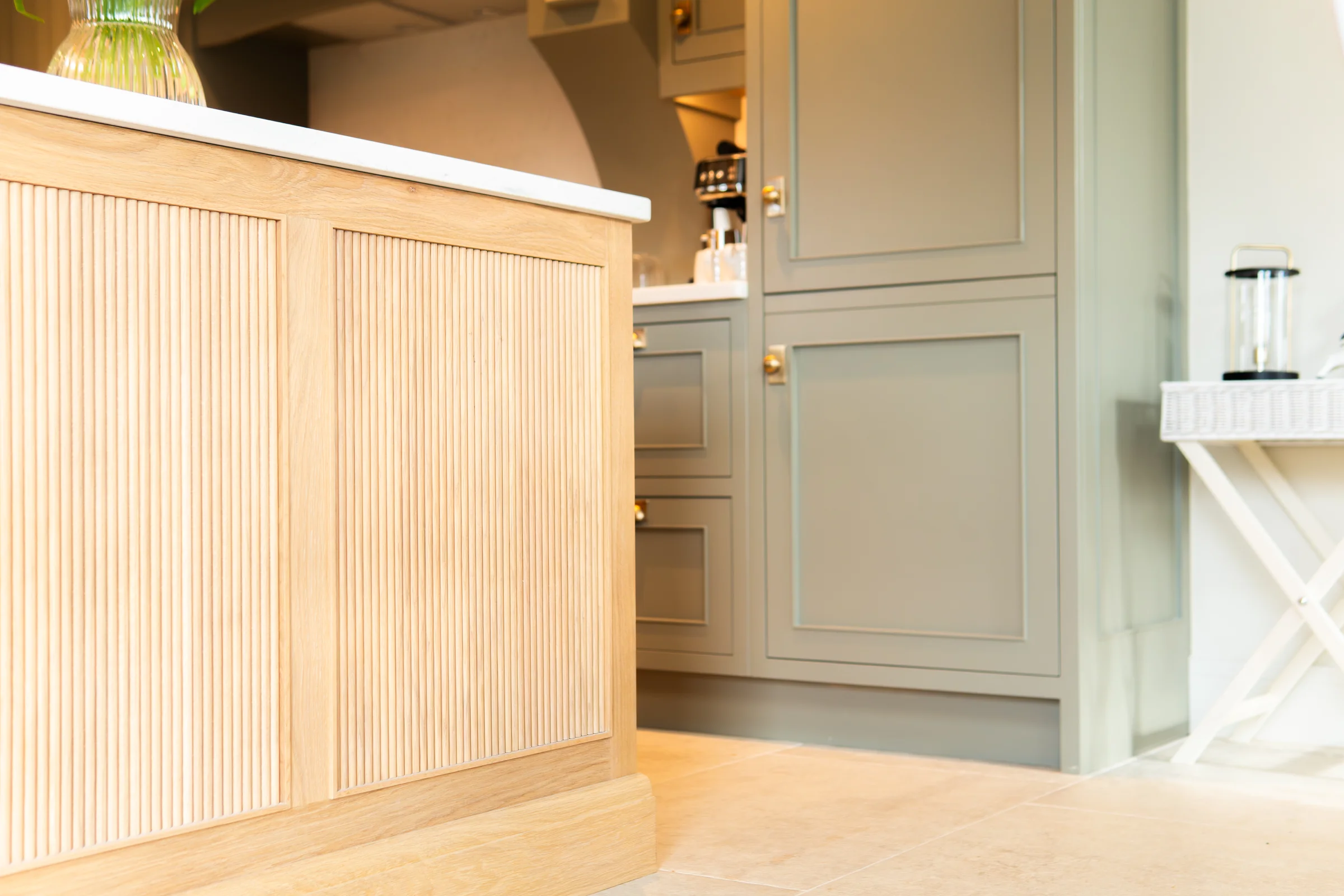 Oak reeded island end panel closeup white quartz edge grey units behind stone floor