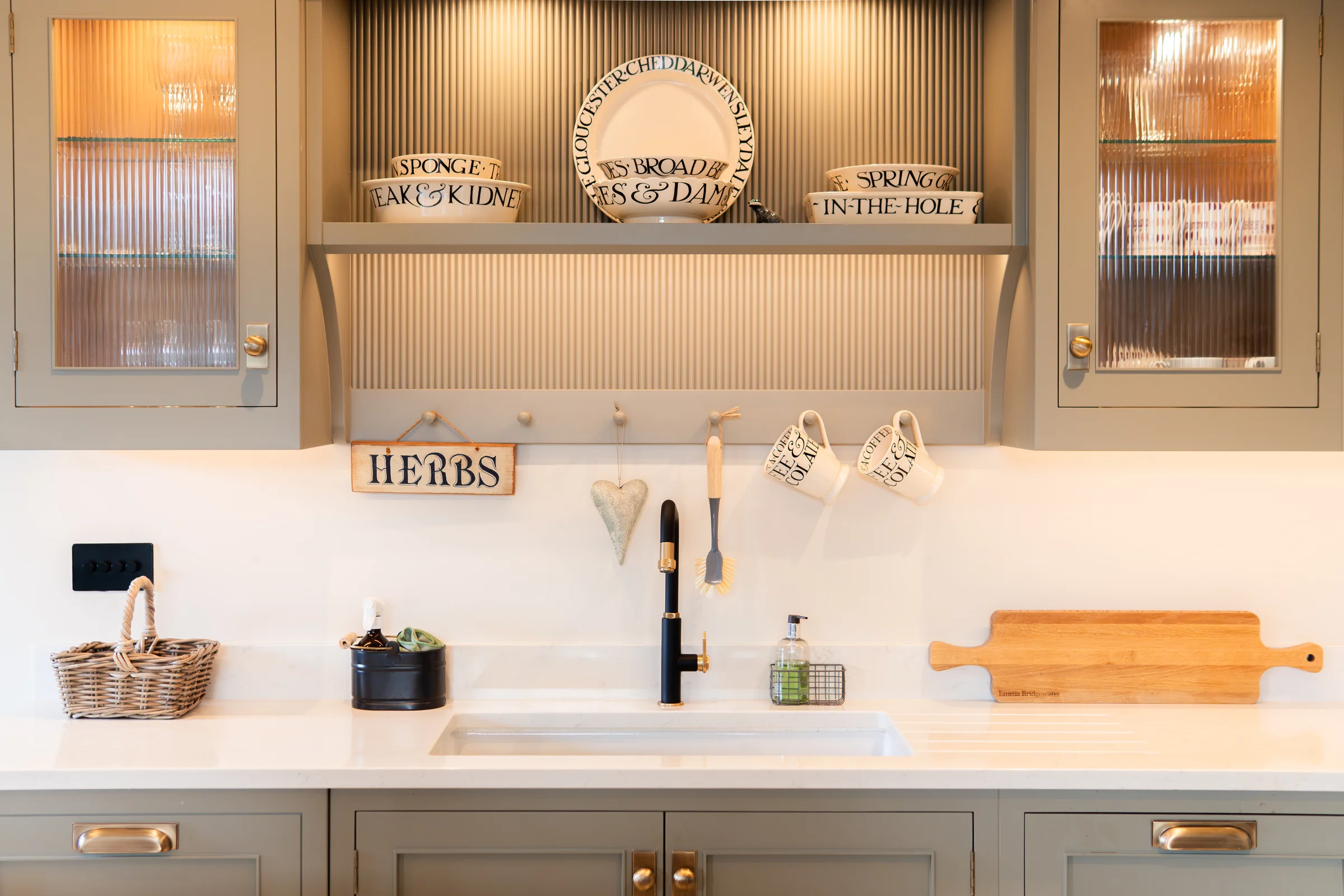 Sink area front on grey shaker reeded glass cabinets open shelf plates black tap brass handles