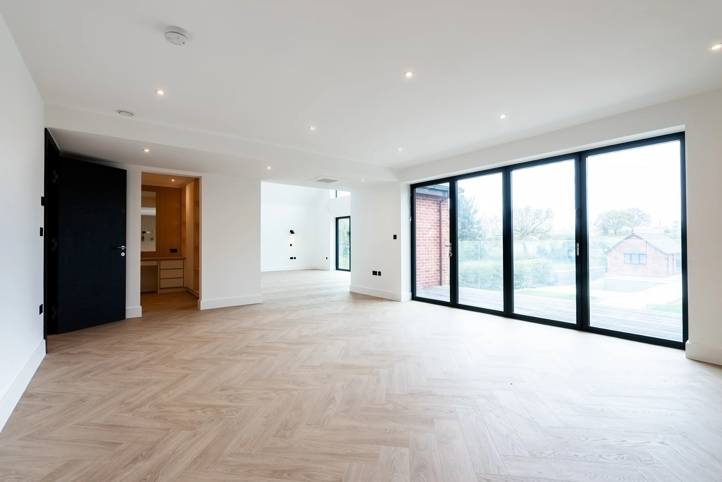Bedroom wide bifold doors garden view black door ensuite herringbone floor