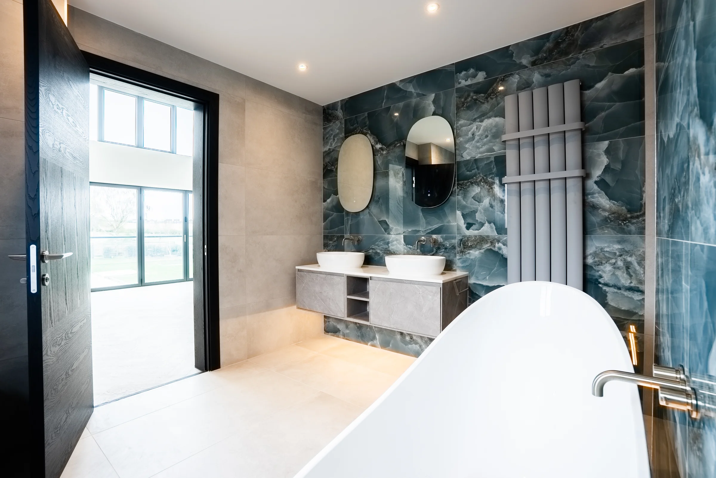 Ensuite wide view blue onyx tiles floating vanity oval mirrors bath radiator