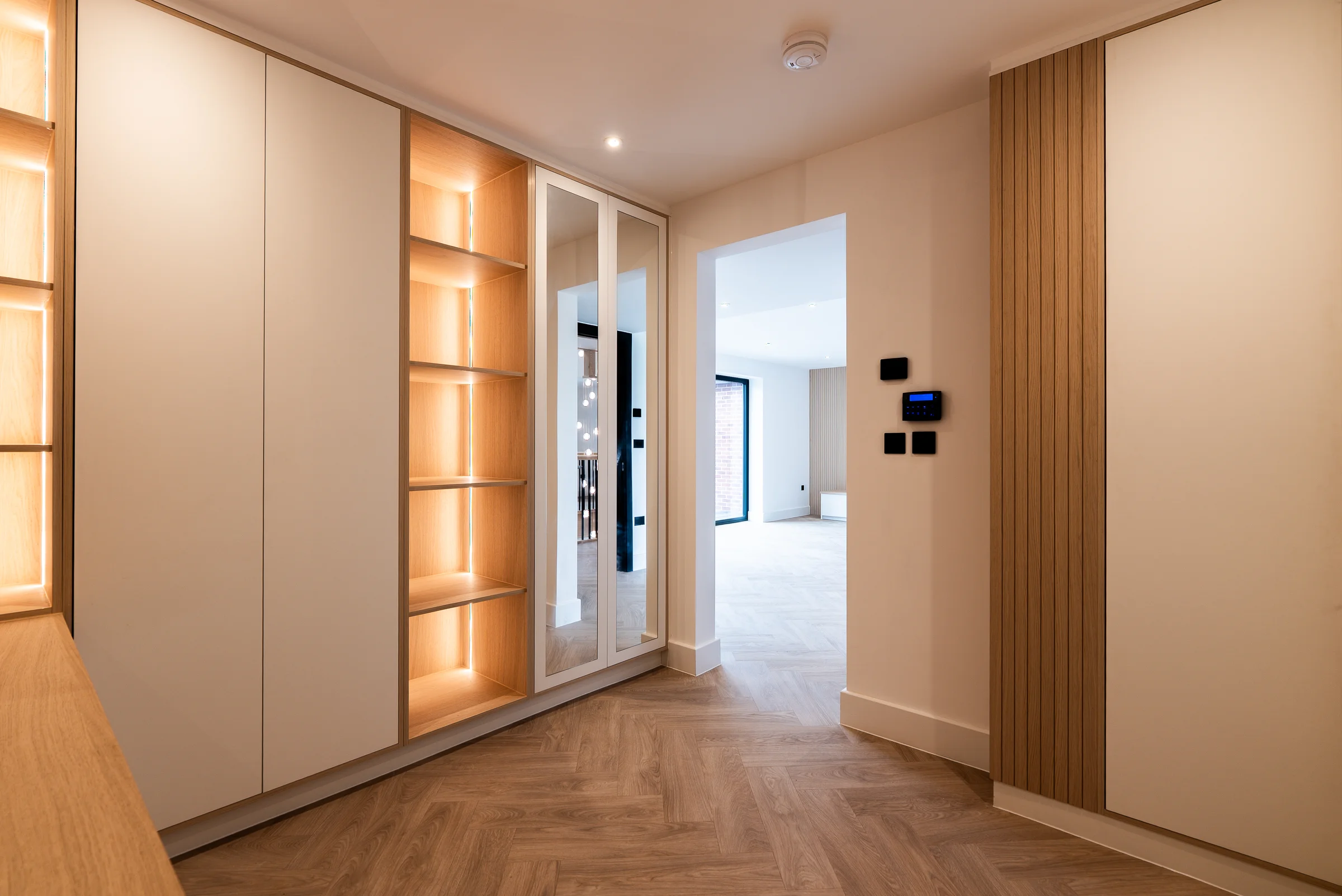 Hallway white wardrobes lit oak shelves mirrored doors smart controls slat wall