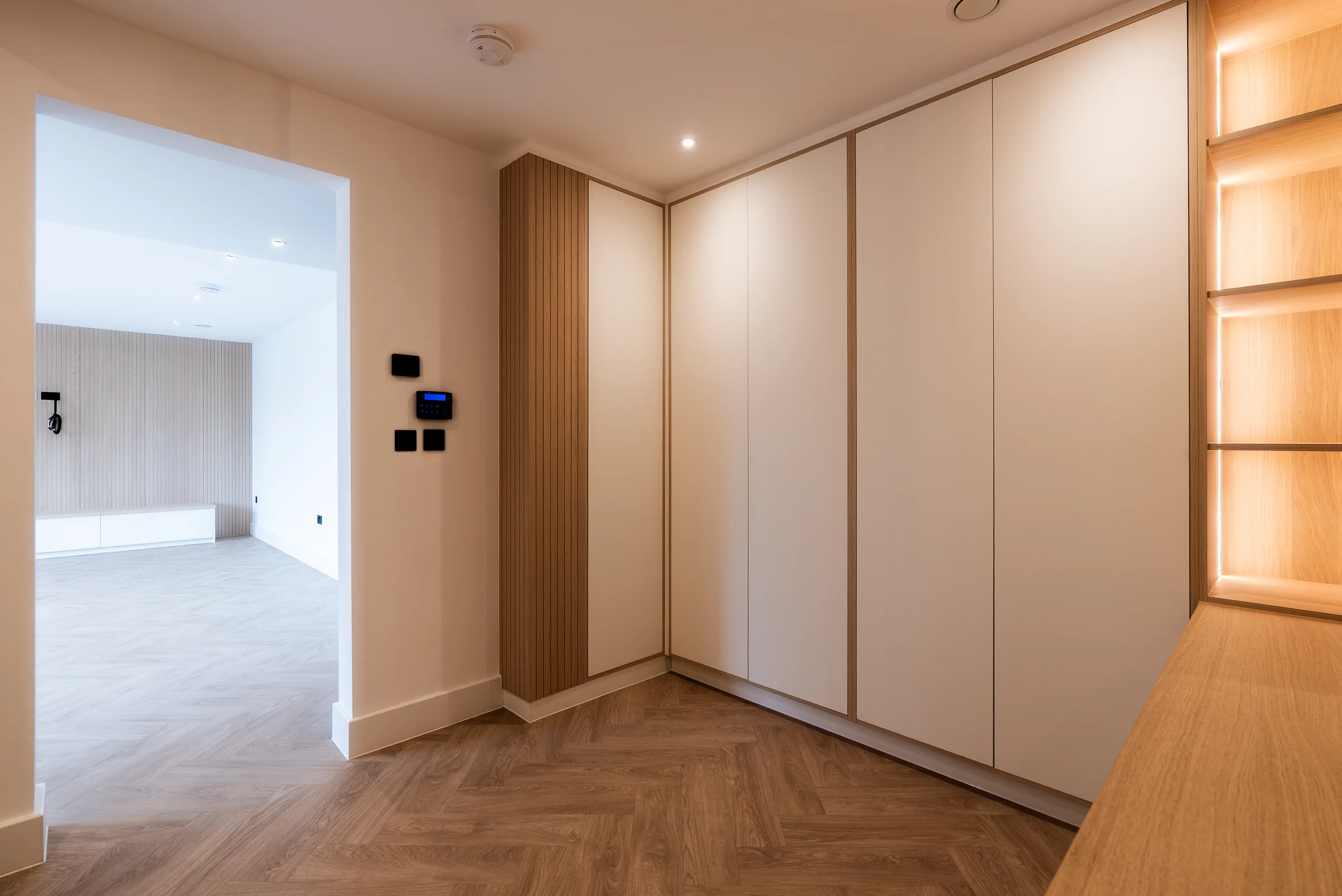Hallway white wardrobes oak slat panels lit shelves smart controls doorway