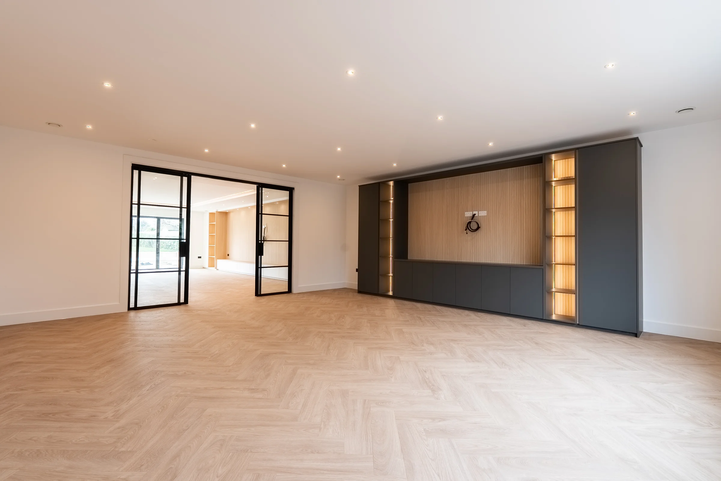 Living room dark grey media wall oak slat panelling led shelves crittall doors