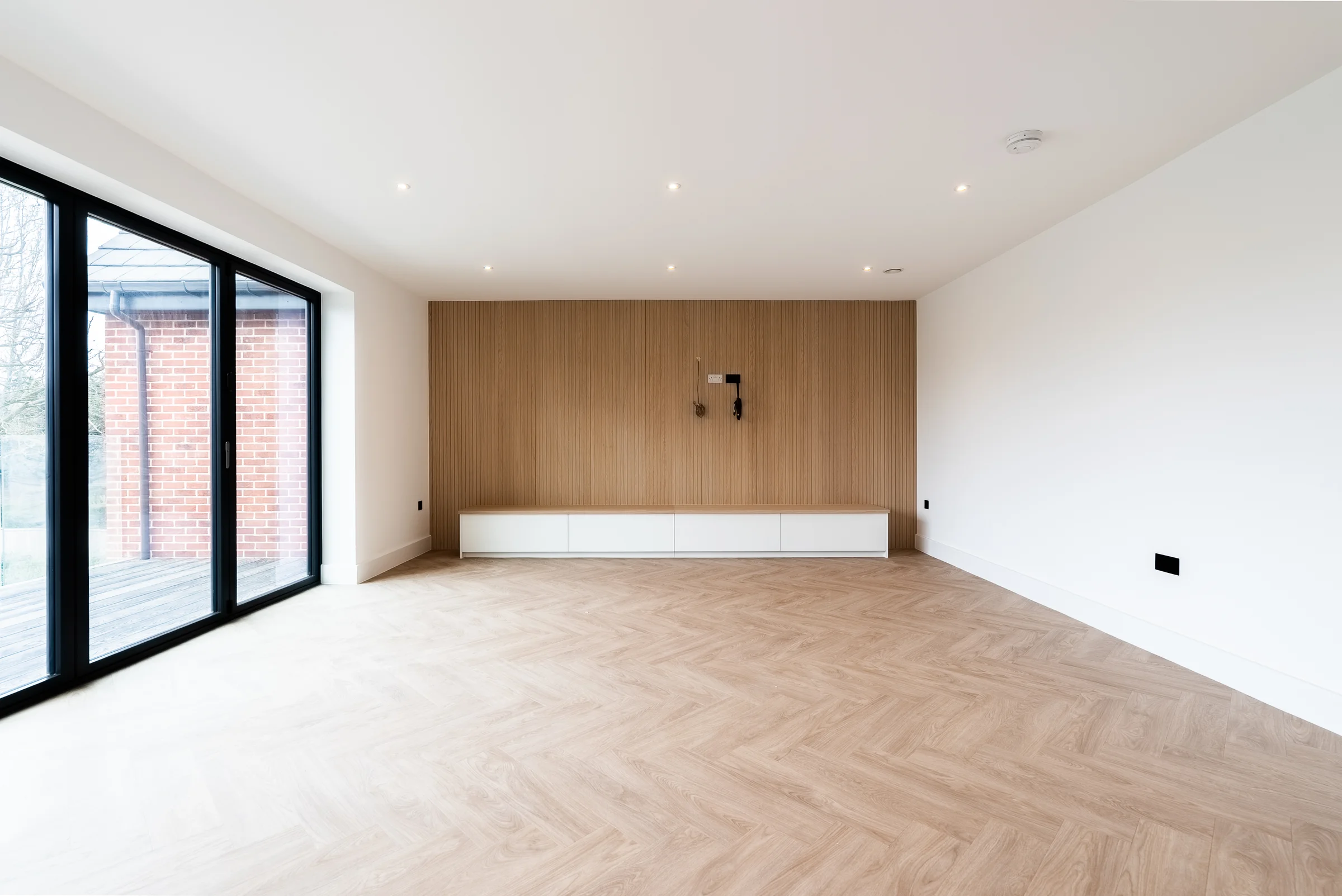 Living room oak slat tv wall white low unit bifold doors garden herringbone