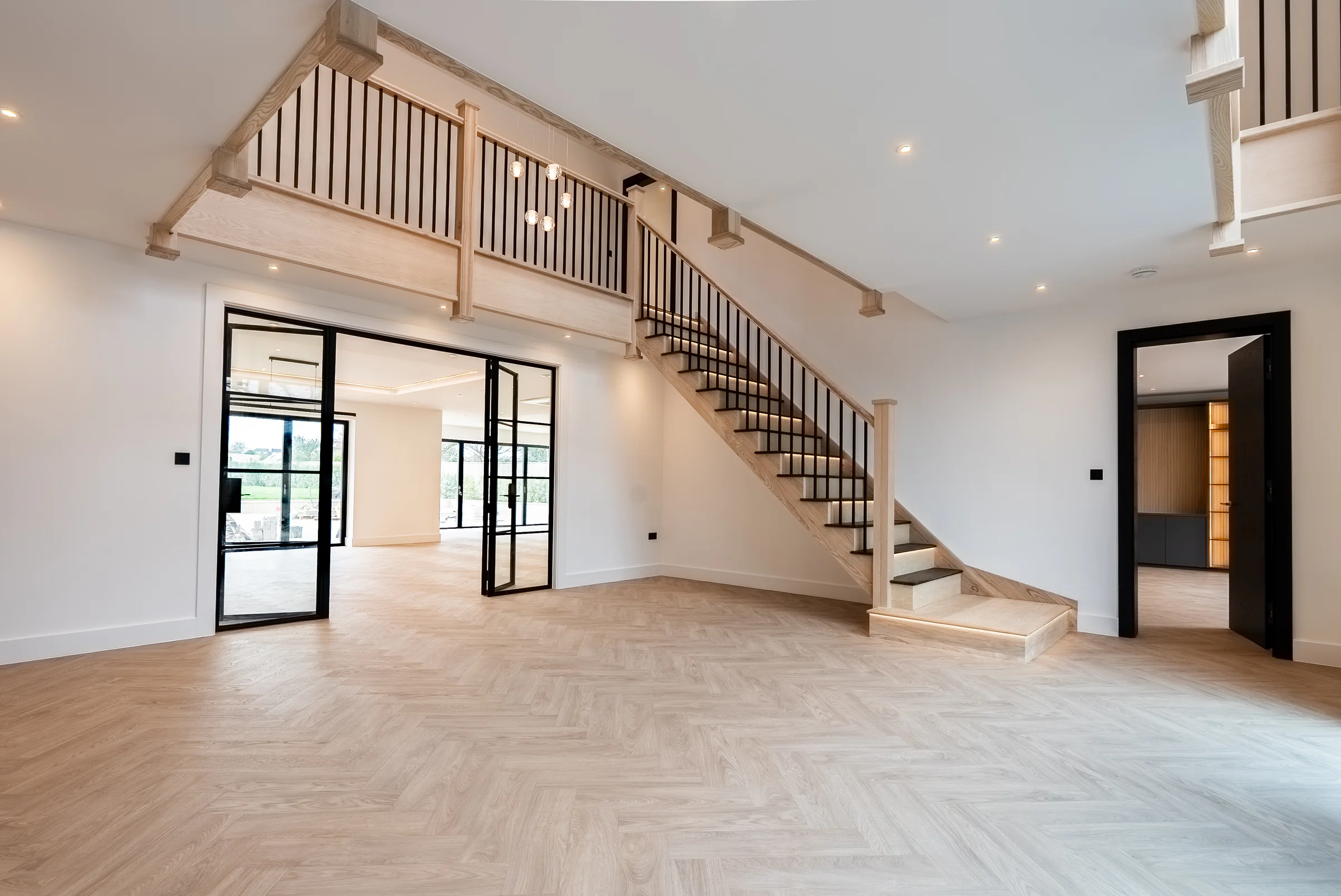 Oak staircase black metal spindles crittall doors herringbone floor hallway