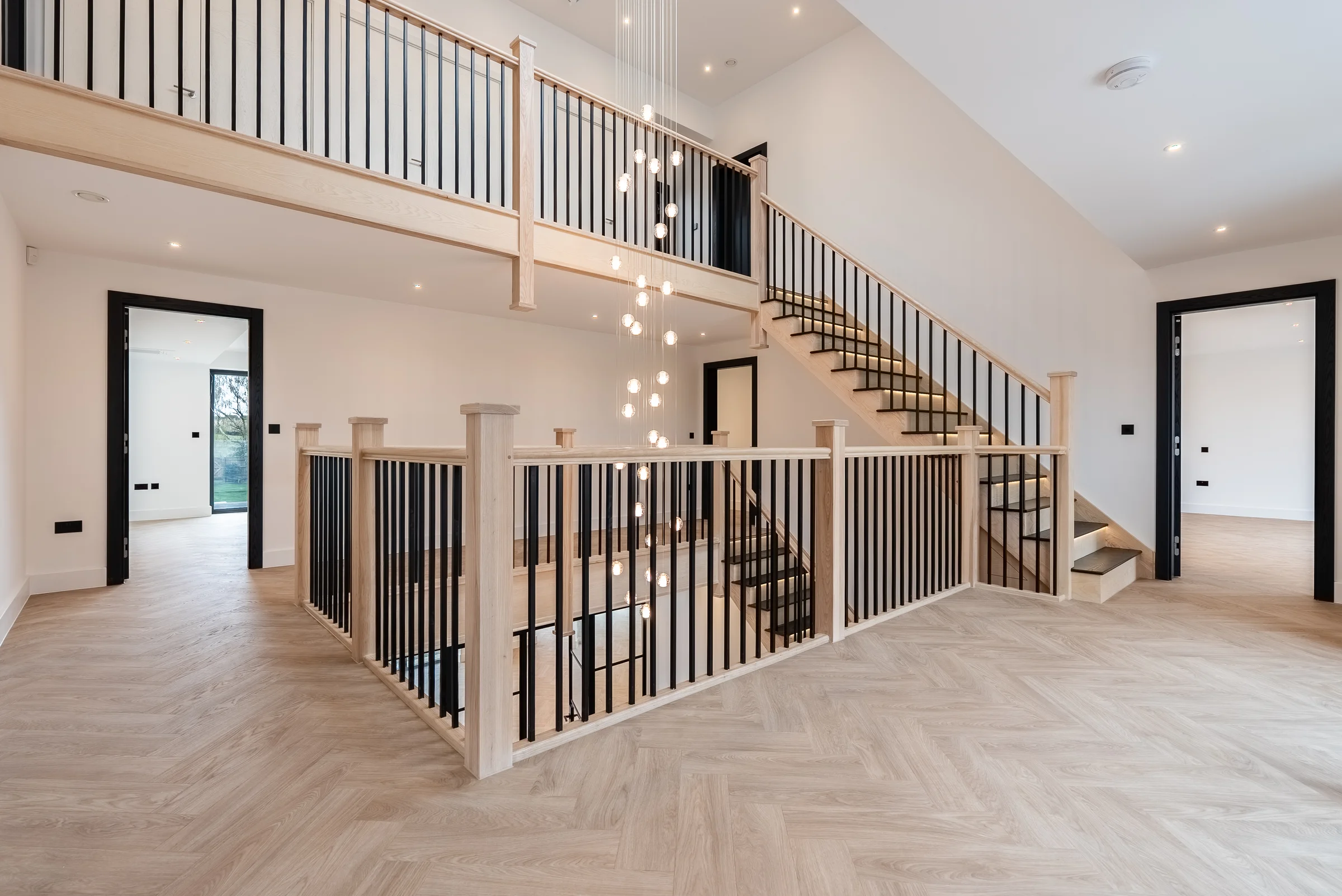 Oak staircase landing black spindles glass pendant chandelier herringbone floor