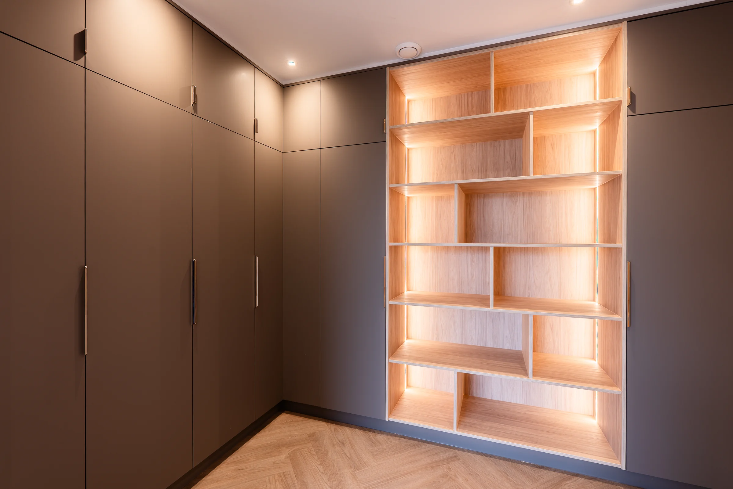 Taupe fitted wardrobes illuminated oak geometric bookcase shelves herringbone
