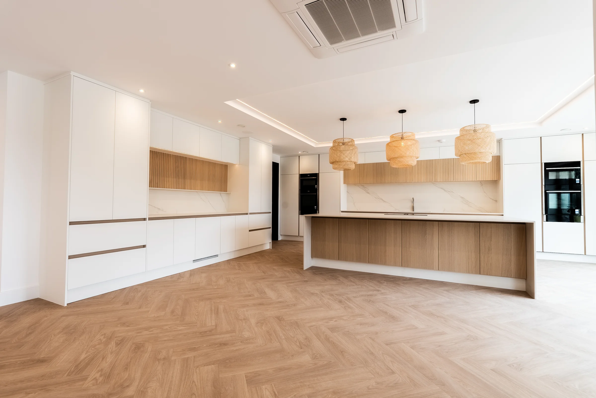 White handleless kitchen wide oak island rattan pendants slat niches marble splashback
