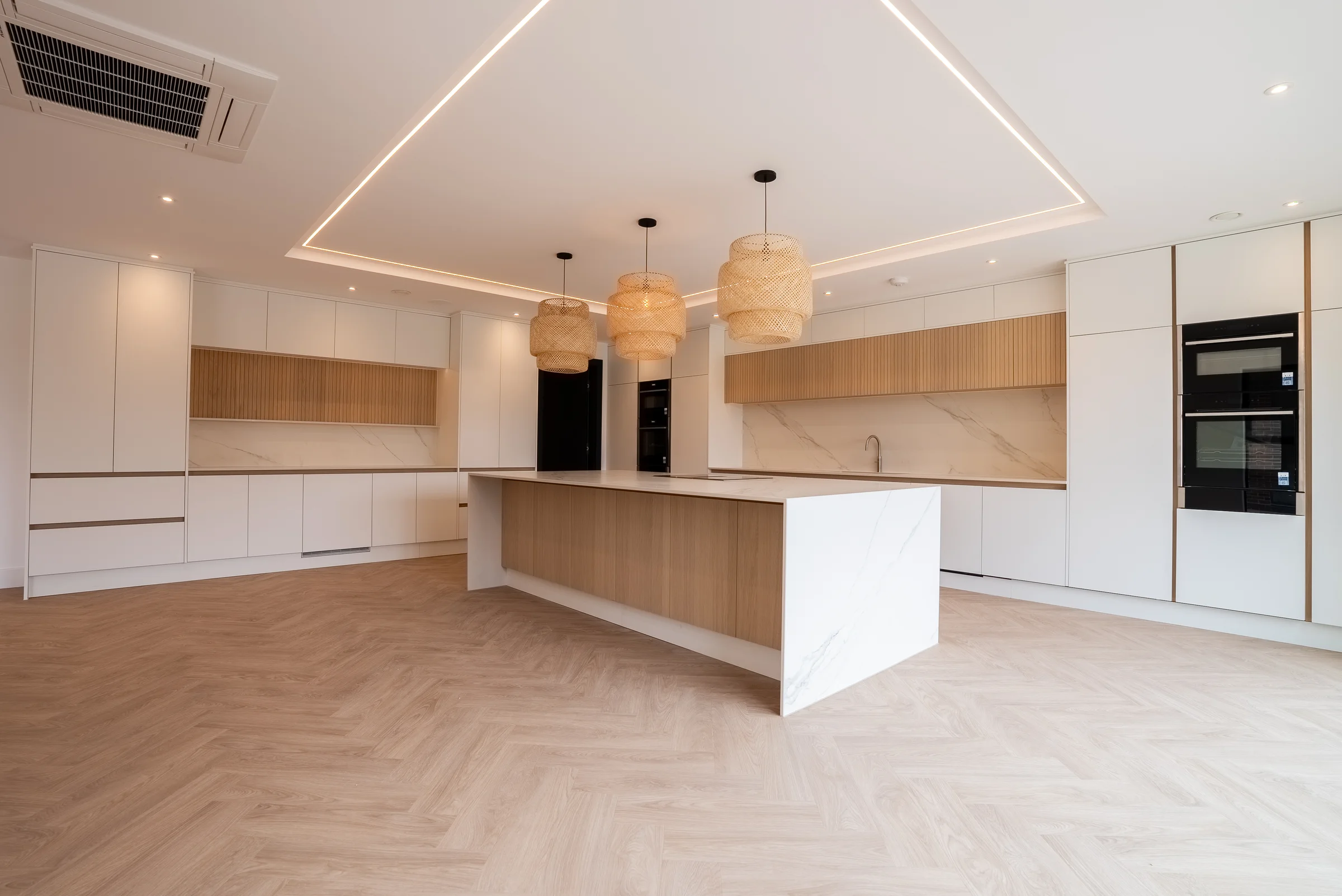 White handleless kitchen oak island marble ends rattan pendants slat niches led ceiling
