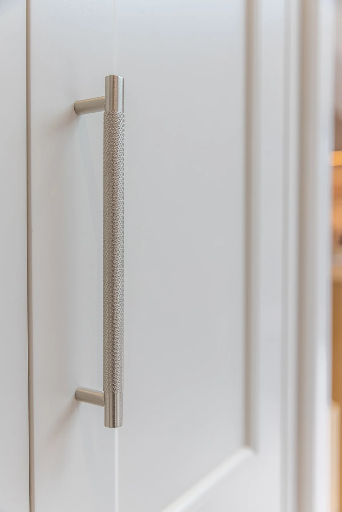 Knurled chrome bar handle detail white shaker door