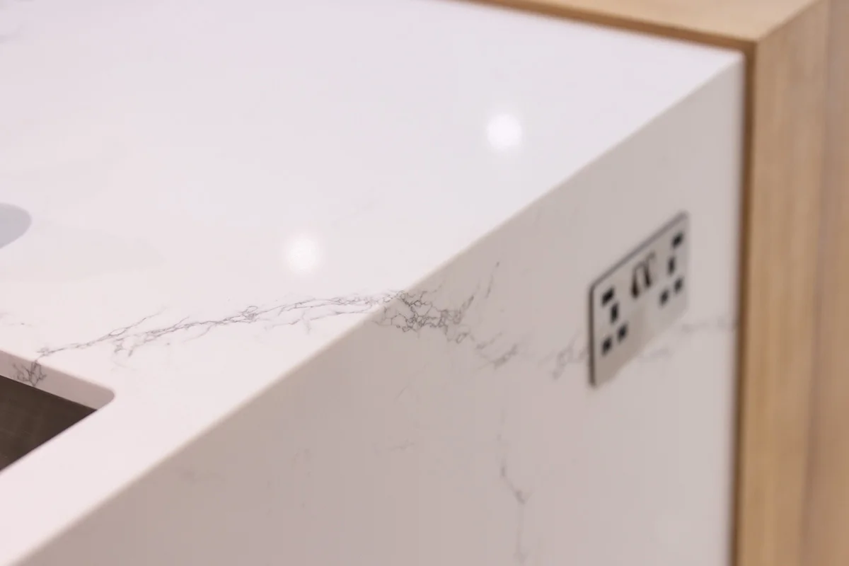 Quartz worktop veining closeup integrated power socket oak trim