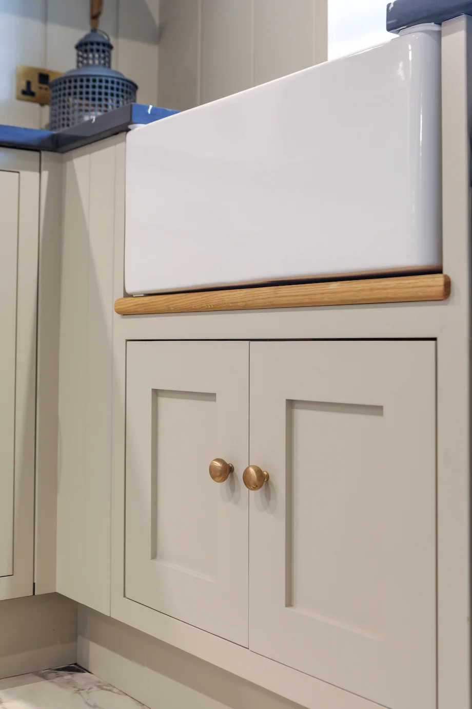 Belfast sink closeup oak trim detail brass knobs grey shaker doors