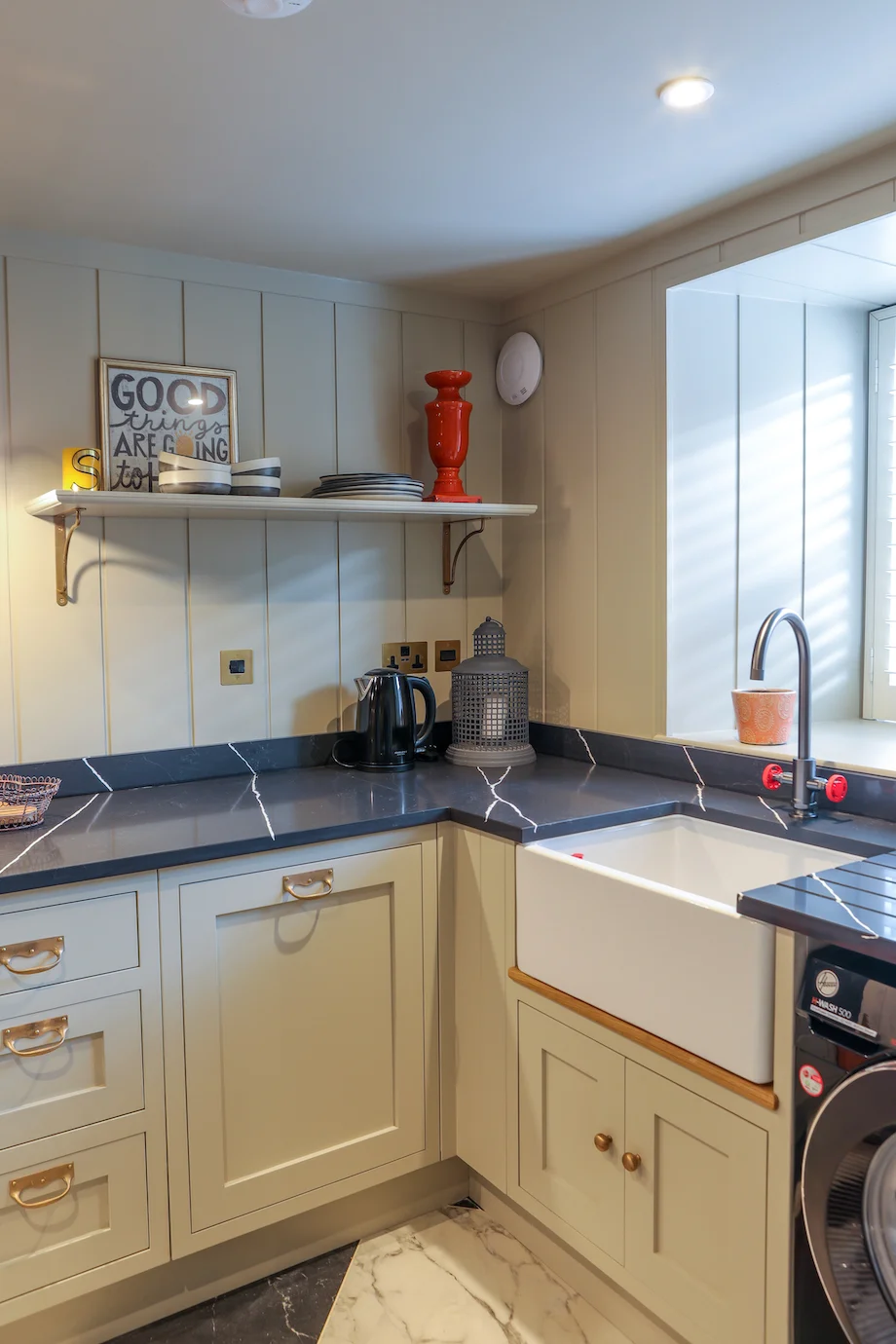 Corner belfast sink brass tap grey units dark quartz panelling shelf window