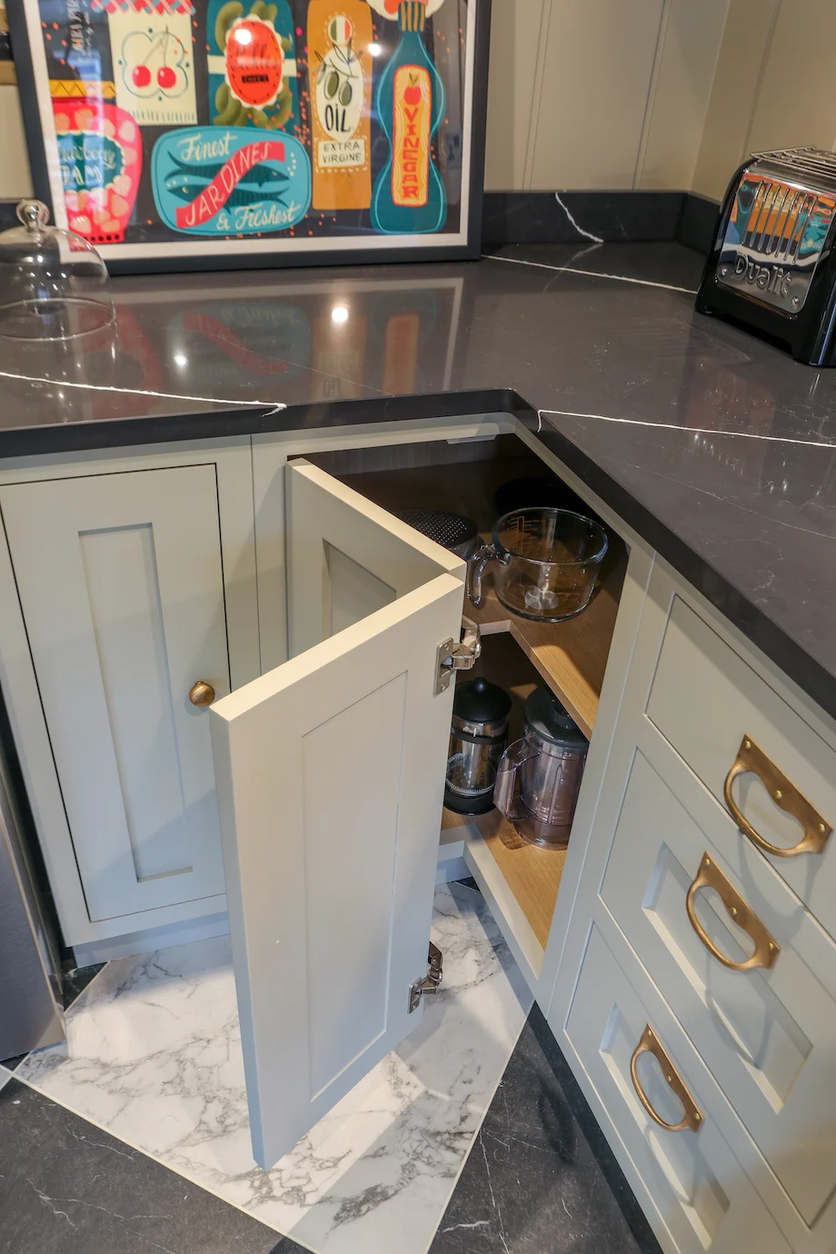 Corner cupboard open from above dark quartz worktop dualit toaster brass handles