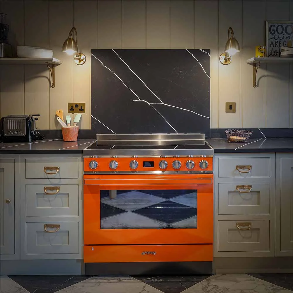 Orange smeg range cooker black marble splashback grey shaker brass handles wall lights