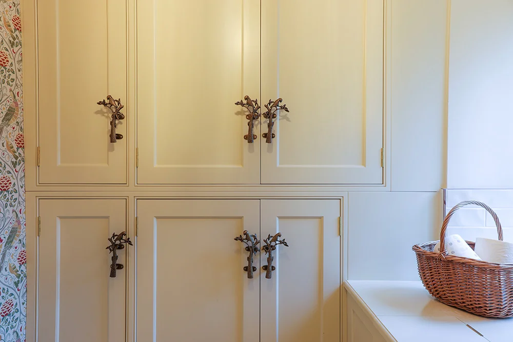 Cream linen cupboards decorative bronze tree branch handles floral wallpaper