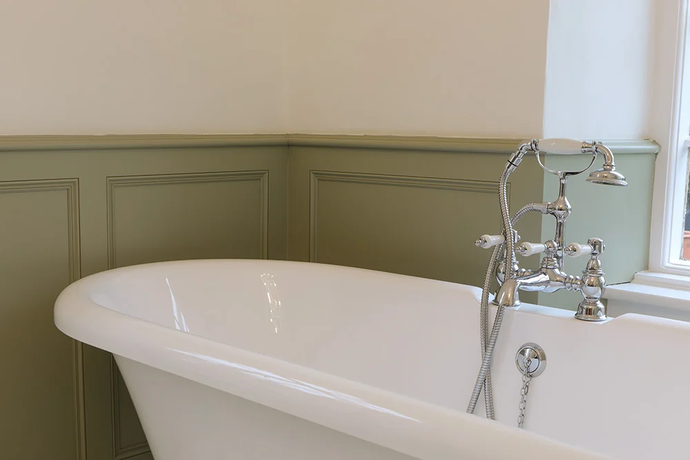 Roll top bath closeup chrome traditional taps sage green panelling