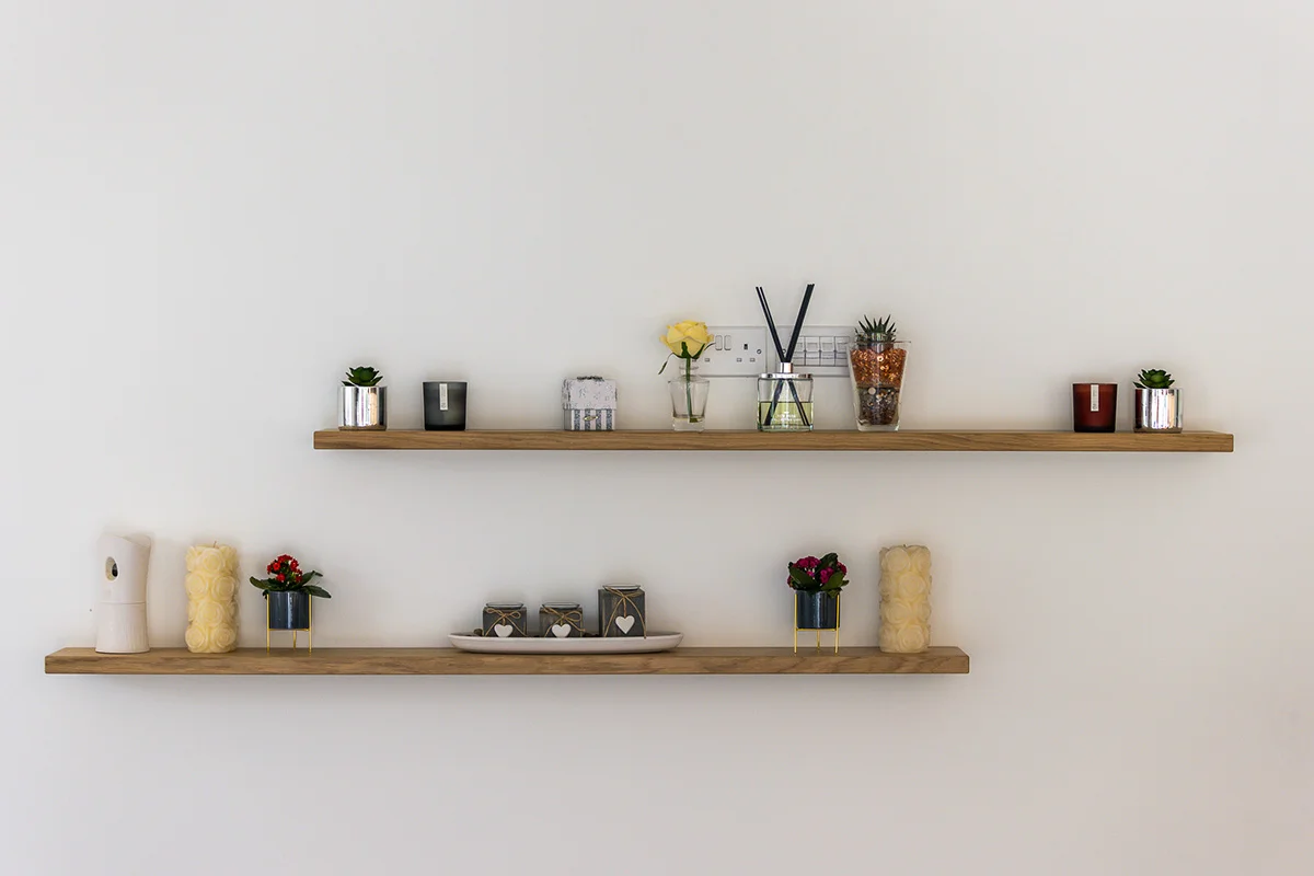 Oak floating shelves candles diffuser plants decorative items white wall