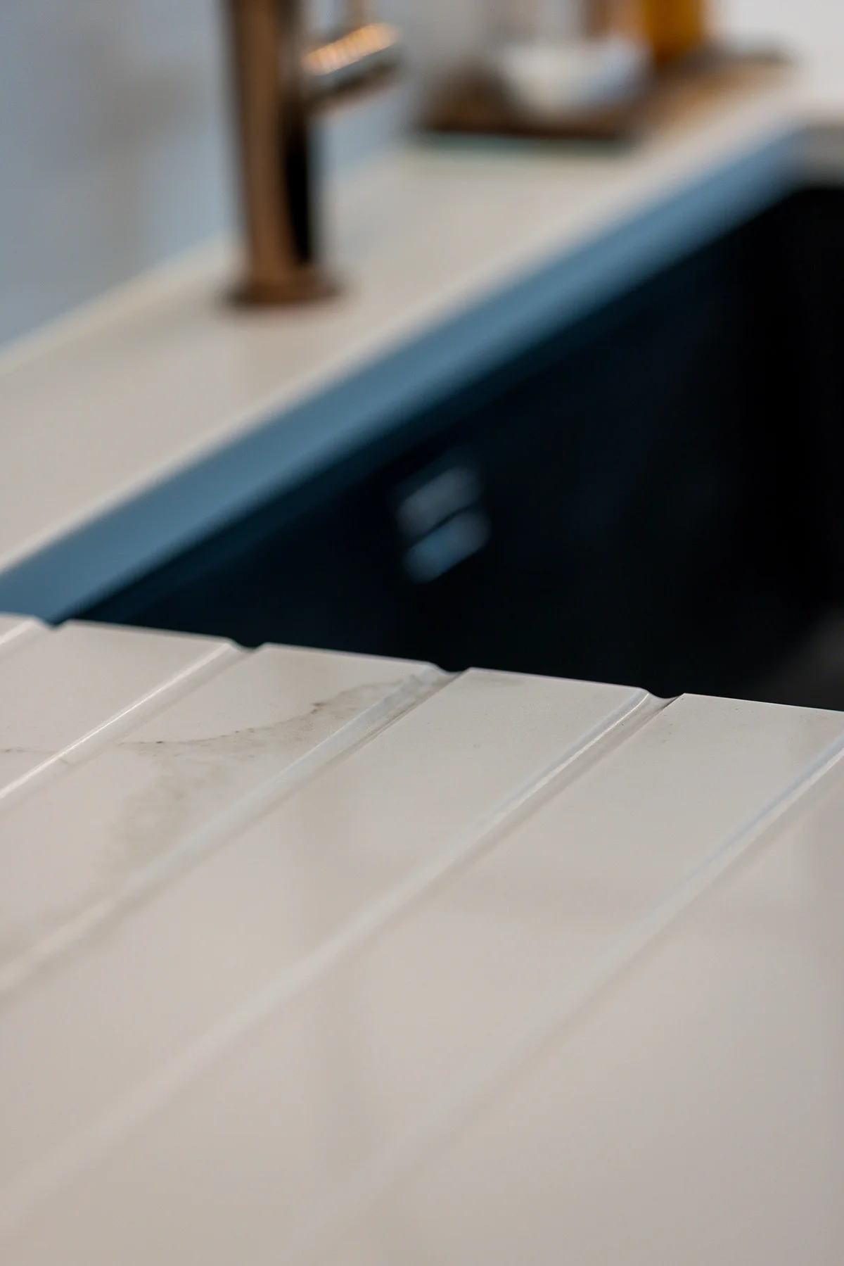 Quartz drainer grooves closeup dark undermount sink brass tap
