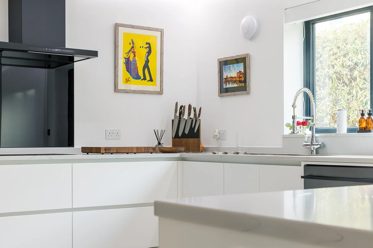 White handleless units quartz worktop black extractor spring tap window