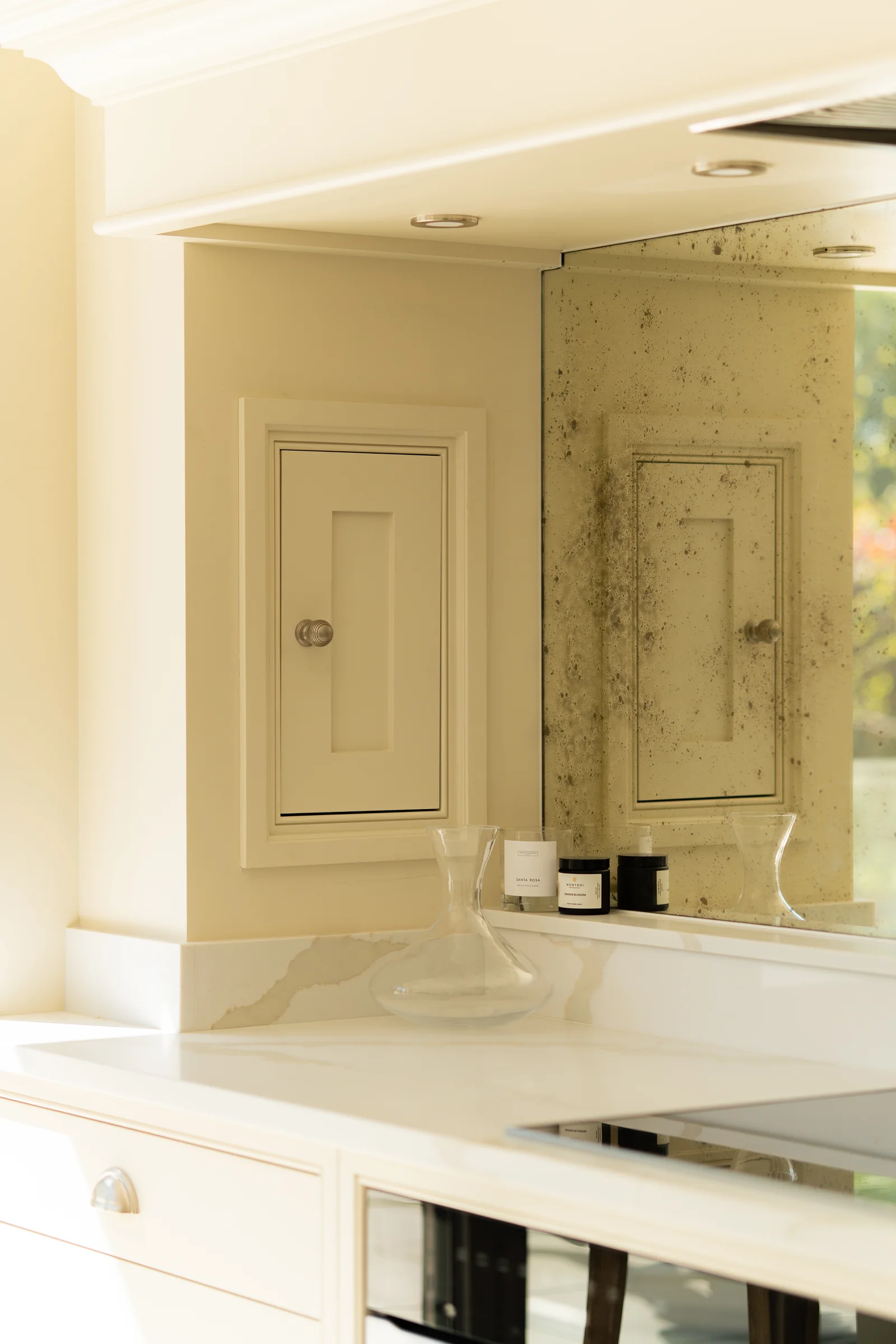 Cream raised panel wall cabinet nickel knob antiqued foxed mirror splashback carafe