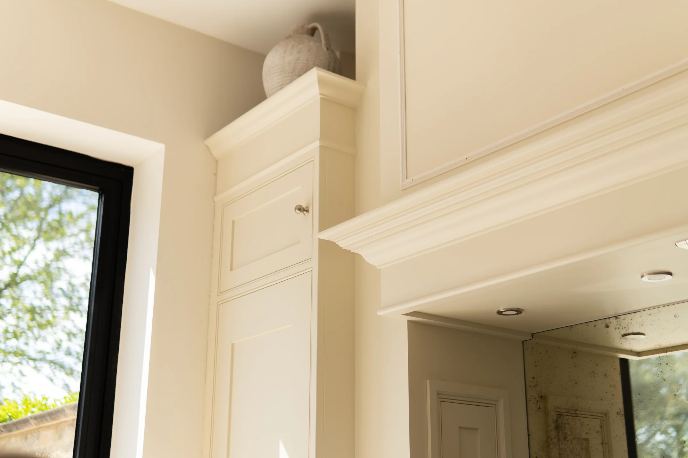 Cream tall cabinet cornice mantel canopy antiqued mirror downlights crittall vase