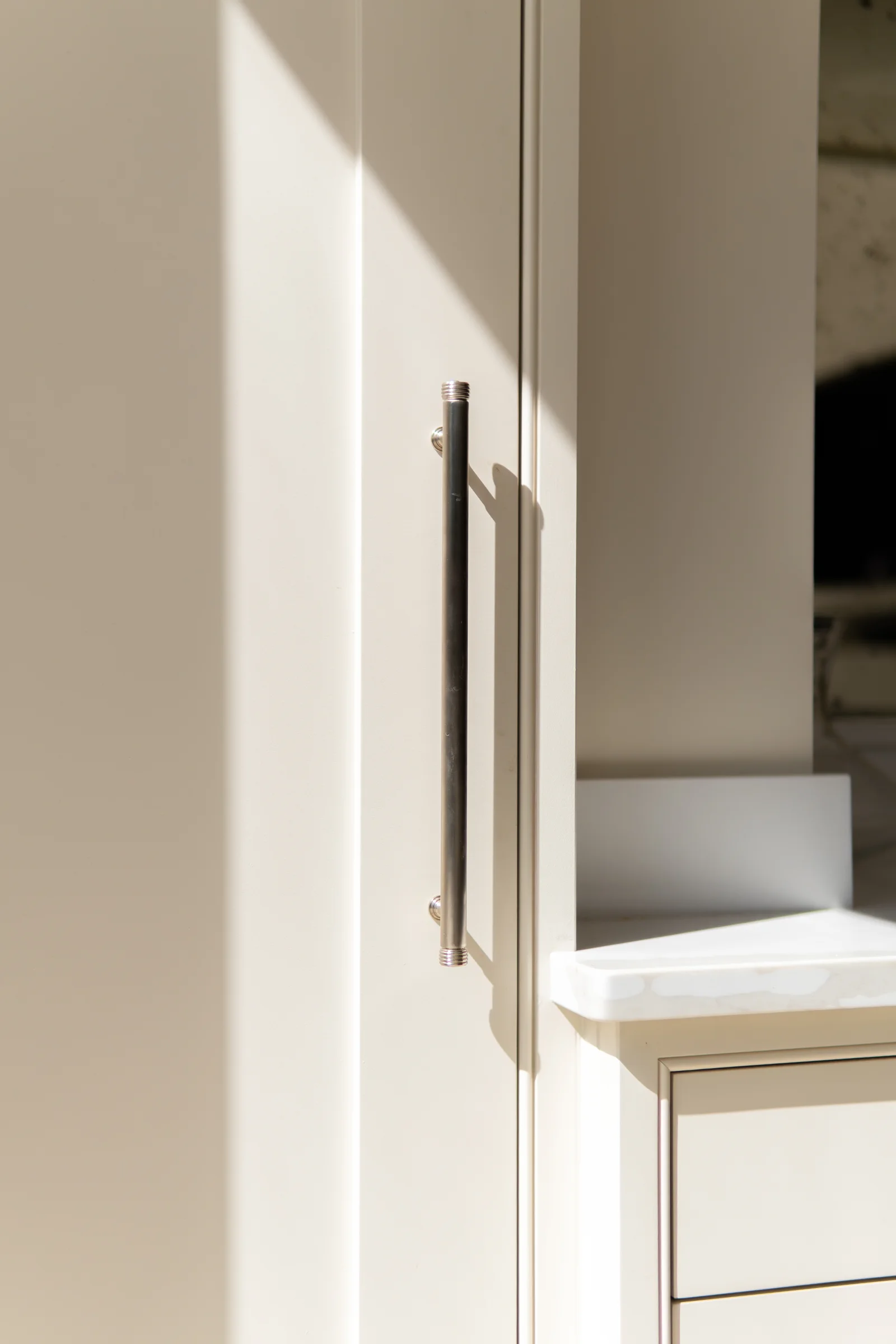 Cream tall unit door closeup nickel bar handle sunlight shadow quartz edge