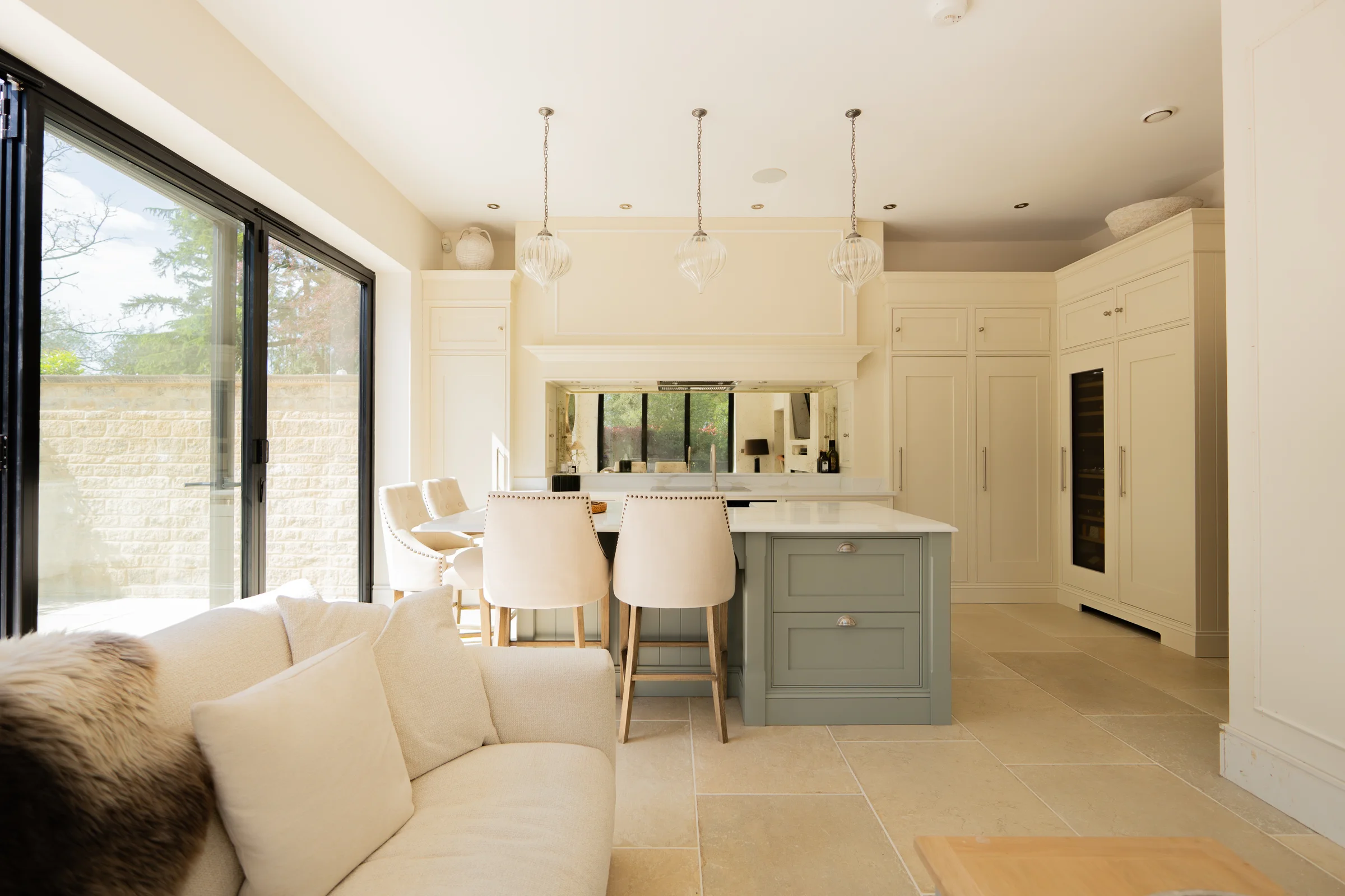 Open plan sofa sheepskin sage island stools pendants cream units wine cooler crittall garden