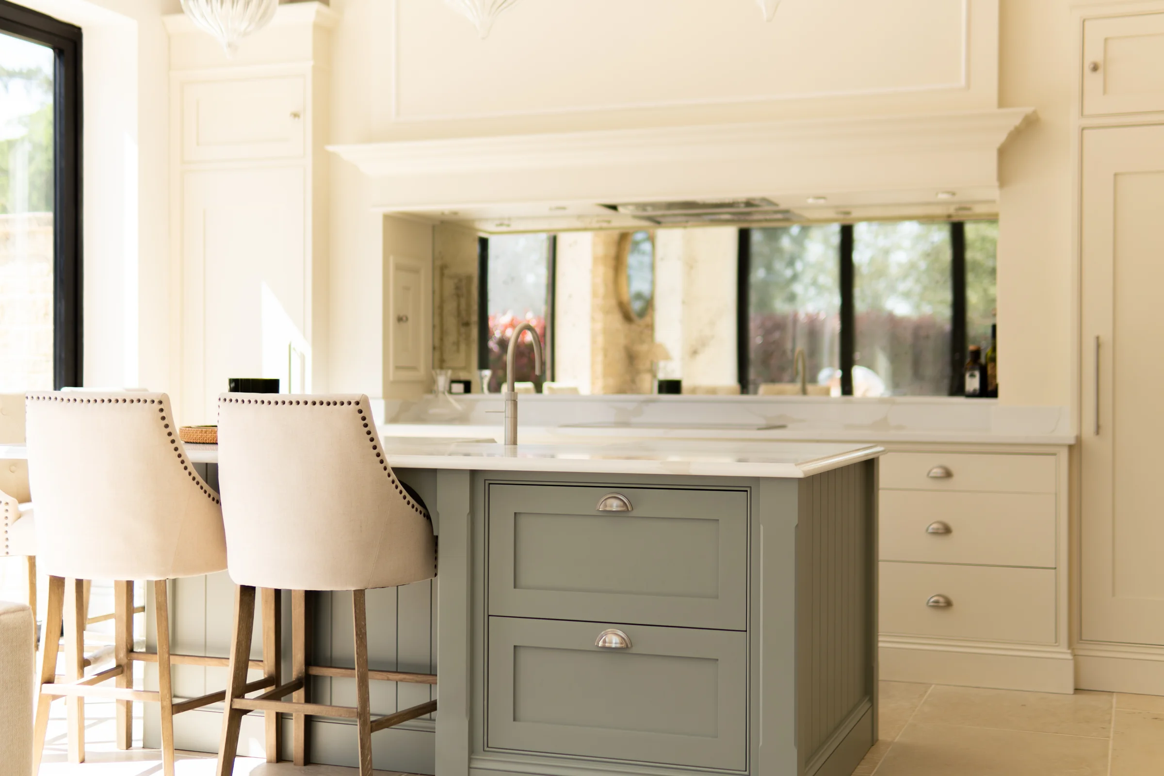 Sage island end studded bar stools cream cabinetry antiqued mirror mantel limestone