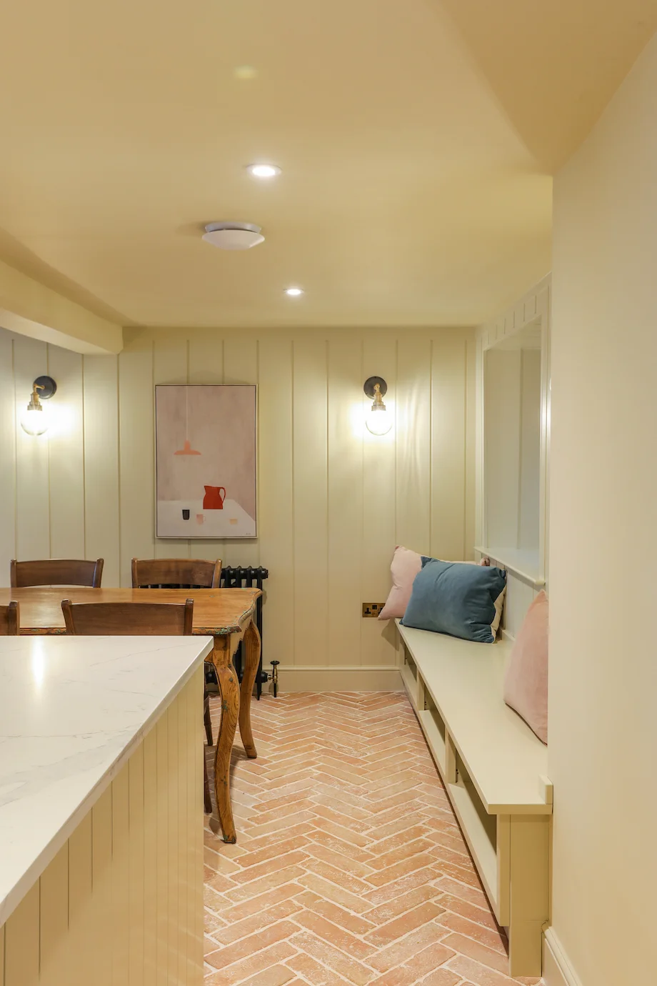 Dining area tongue groove panelling banquette bench cushions globe wall lights art