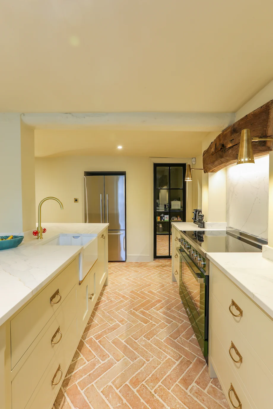Galley view island sink range cooker beam crittall pantry door fridge brick floor