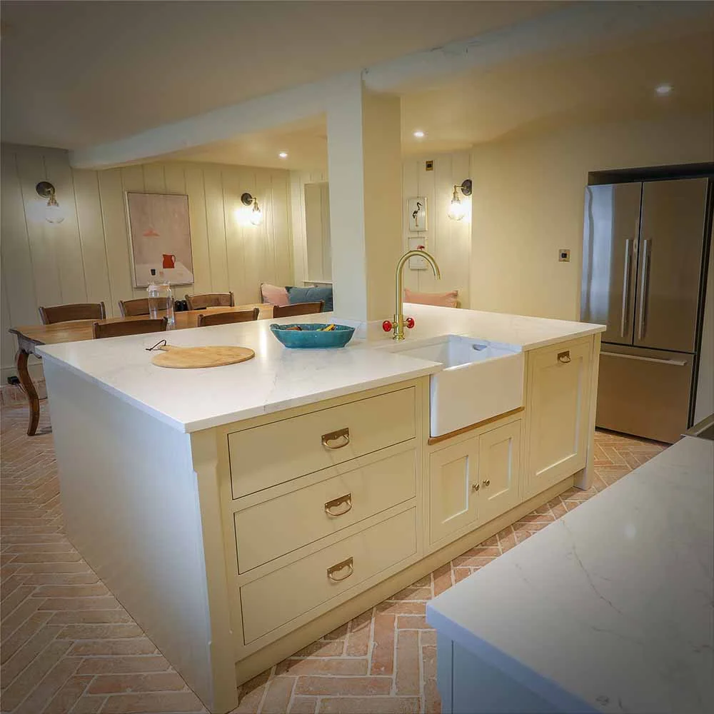 Cream panelled island belfast sink brass tap red handles quartz herringbone brick floor