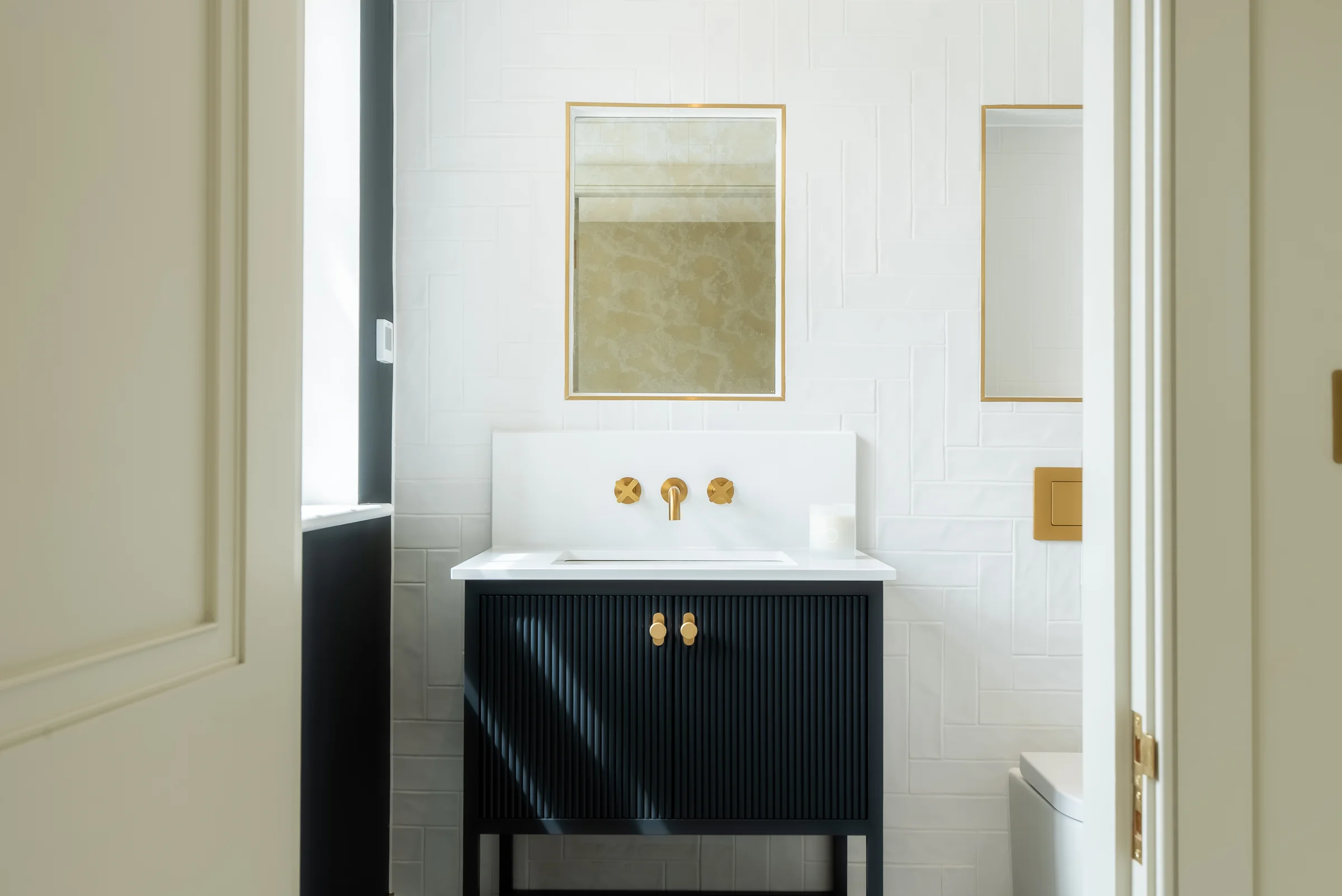 Cloakroom dark navy reeded vanity brass knobs taps mirror white herringbone tiles