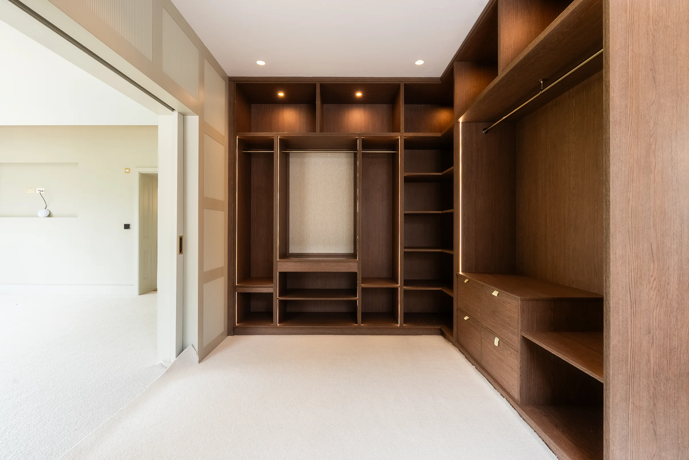 Dressing room opposite angle dark oak wardrobes shelves rails sliding door bedroom