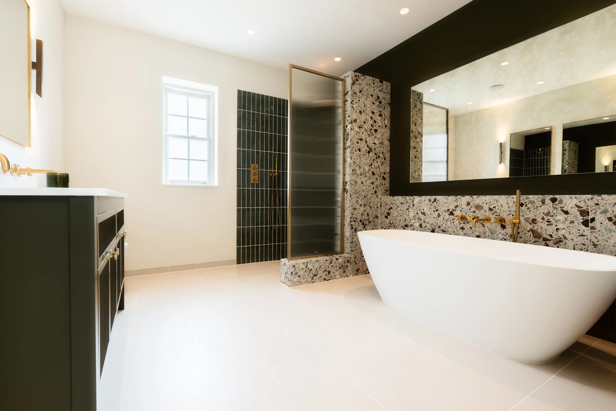 Ensuite freestanding bath terrazzo wall dark green tiles shower reeded glass brass