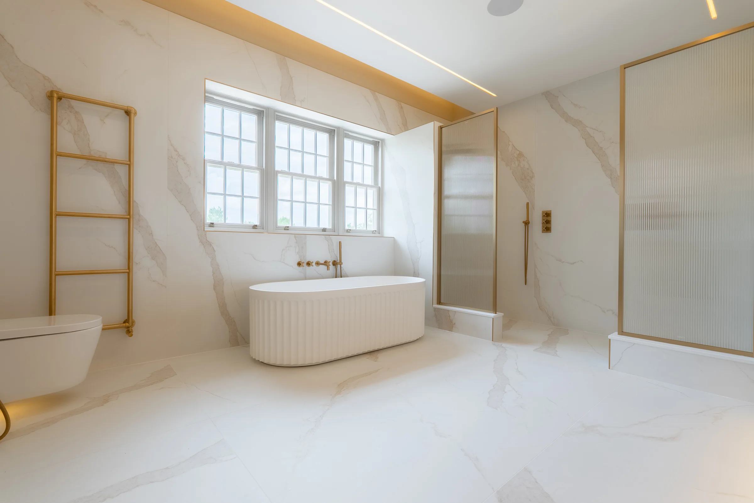 Full ensuite wide fluted bath brass towel rail toilet reeded glass shower marble led