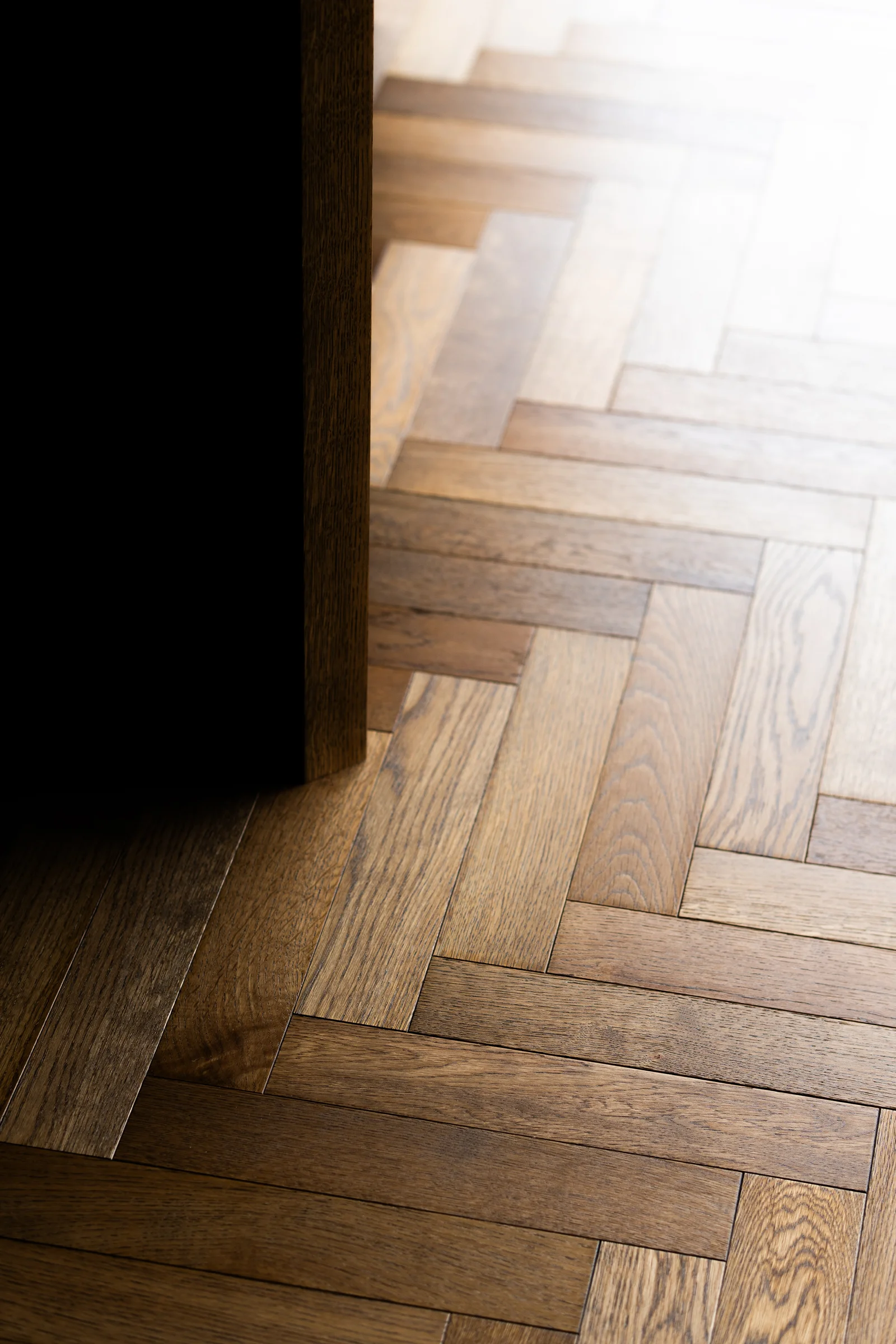 Herringbone parquet oak floor detail dark island base sunlight