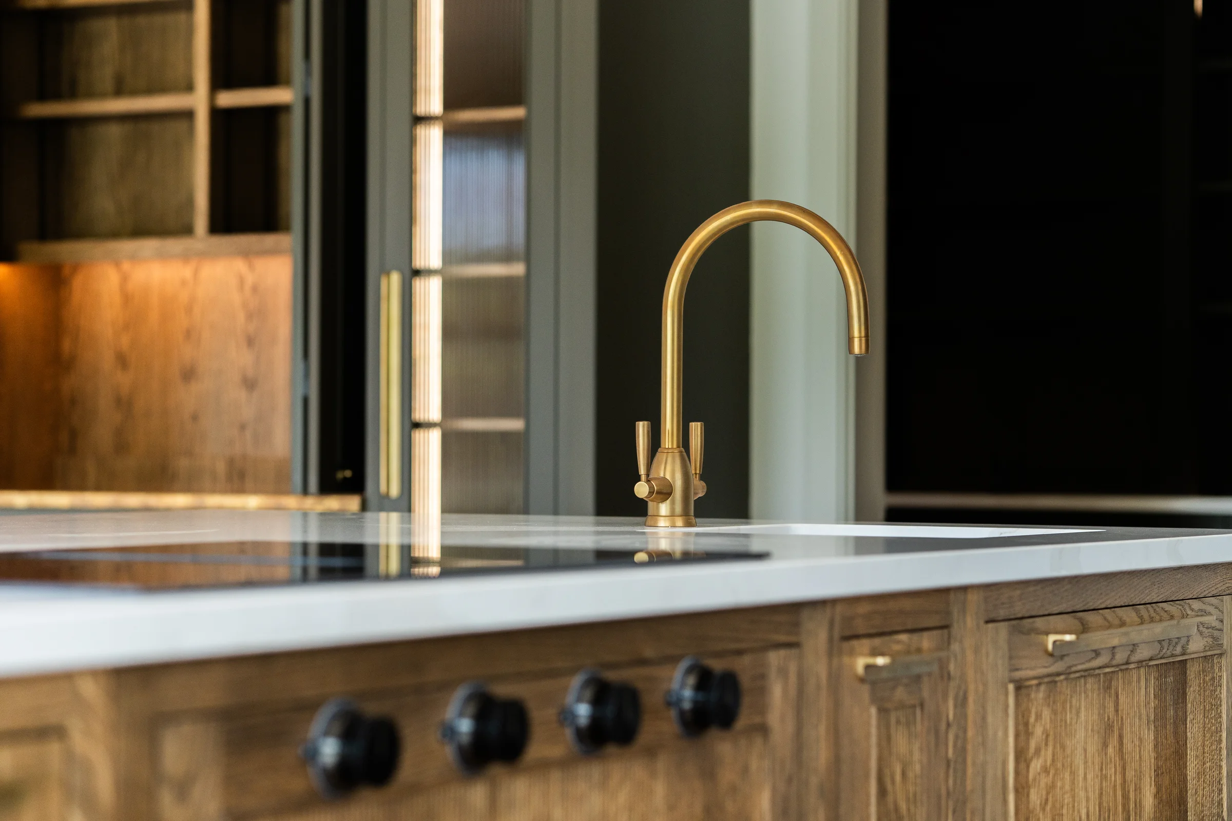 Island detail brass tap white quartz dark oak induction hob knobs dresser