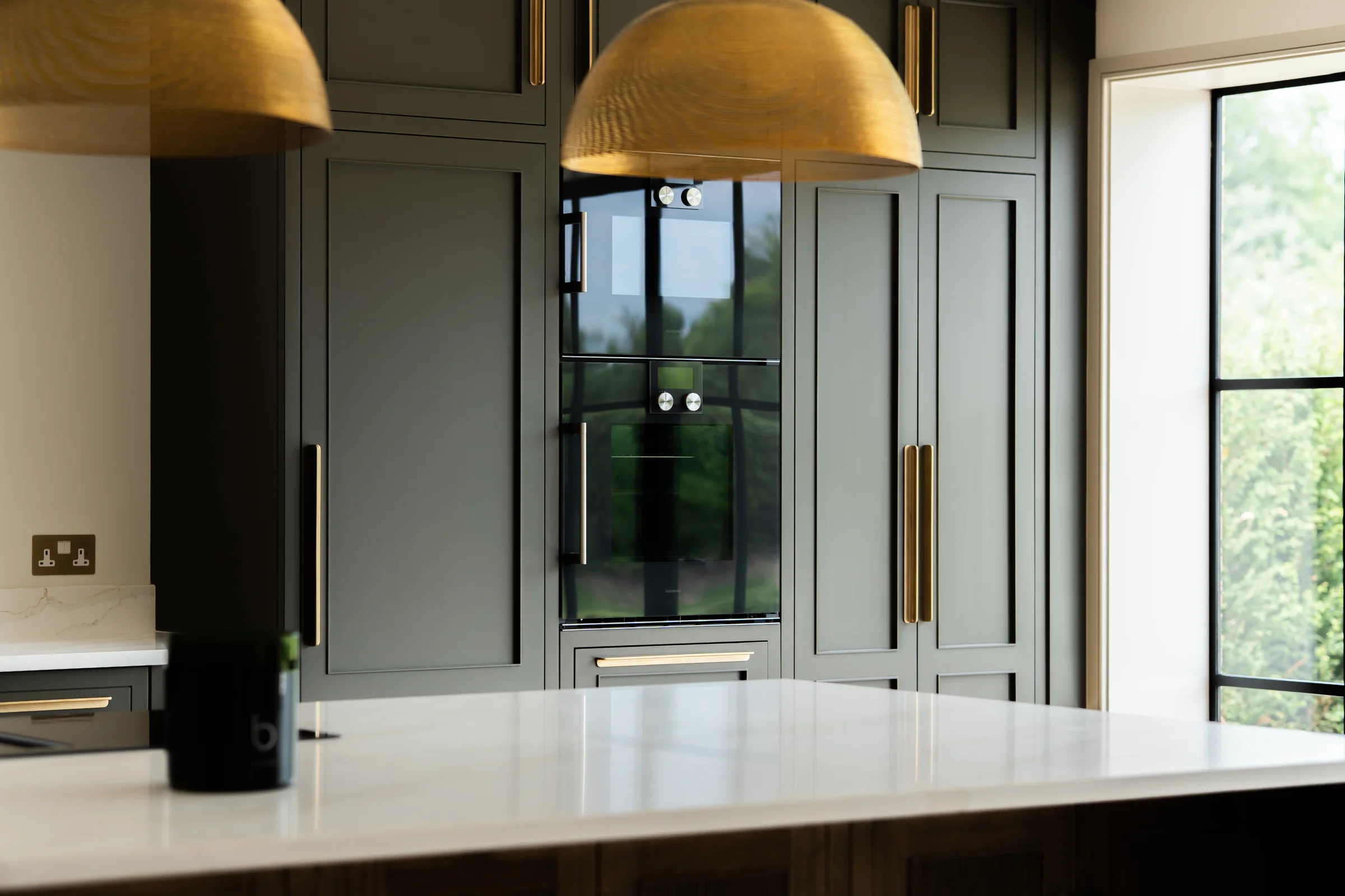 Kitchen detail charcoal tall units brass dome pendants quartz island black oven crittall