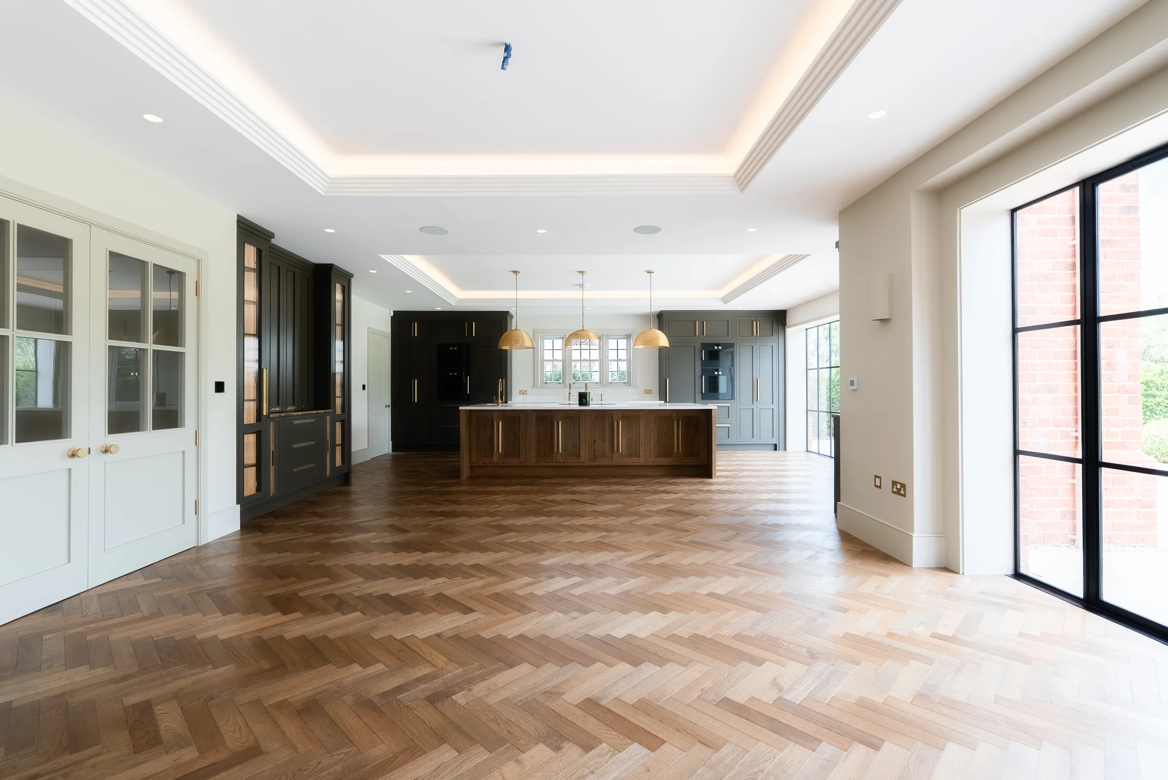Wide kitchen from living white pantry doors dark dresser oak island crittall brick exterior