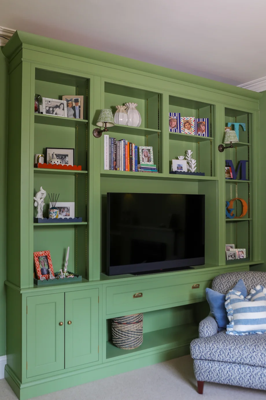 Green media cabinet closeup shelves scallop trays wall lights brass knobs