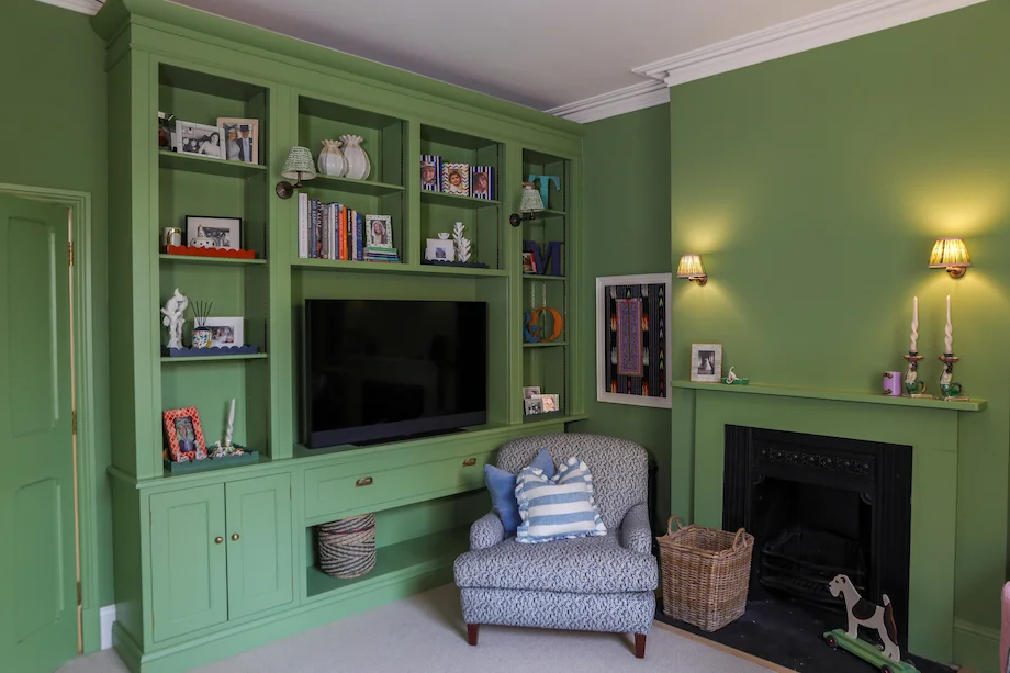 Green sitting room wide view media cabinet fireplace armchair wall lights candles