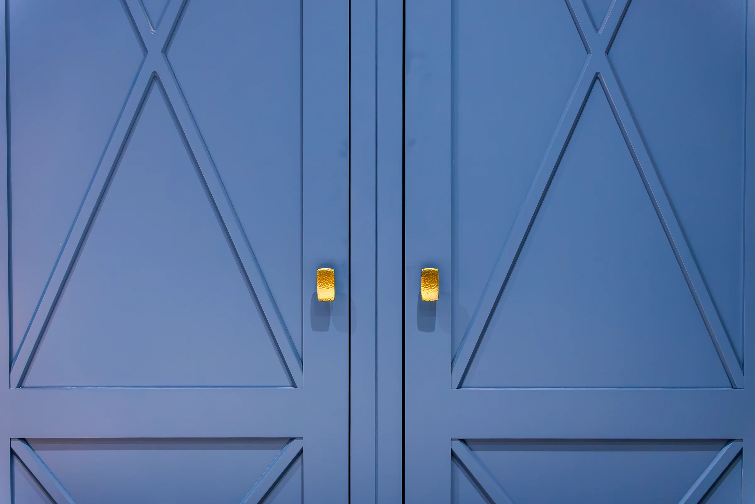Closeup blue x pattern wardrobe doors textured brass knobs detail