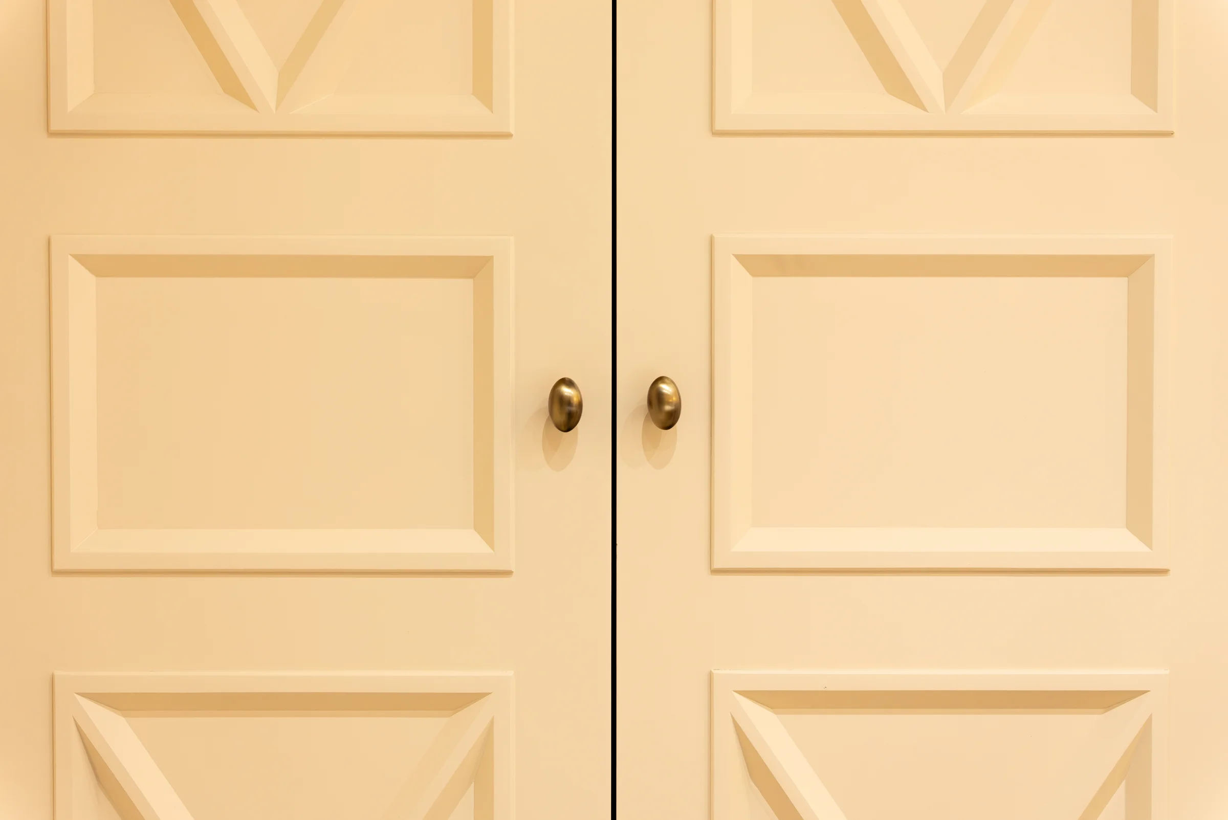 Closeup cream x pattern wardrobe doors brass oval knobs detail