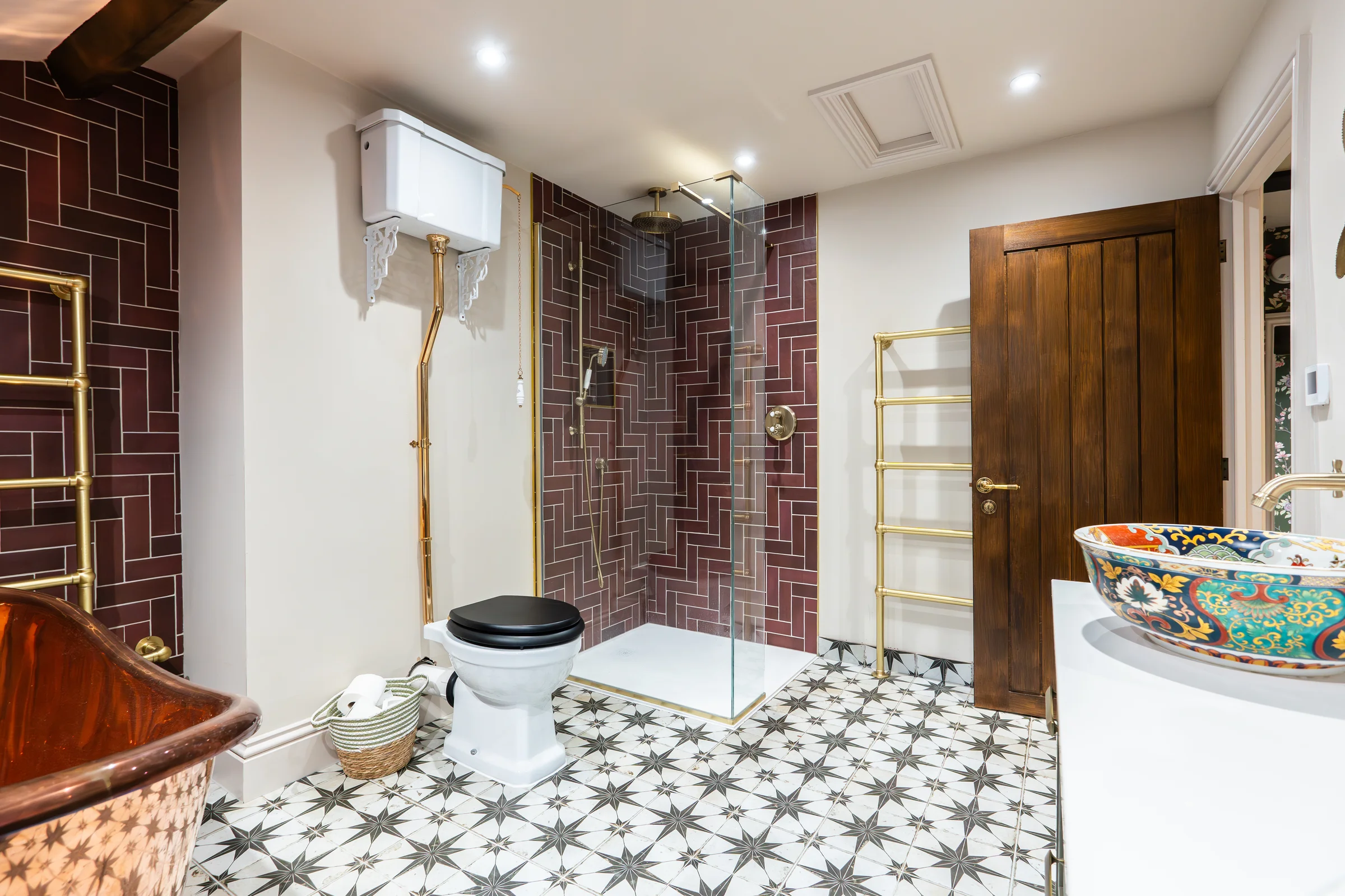 Shower area burgundy herringbone tiles brass fittings glass screen towel rail star floor